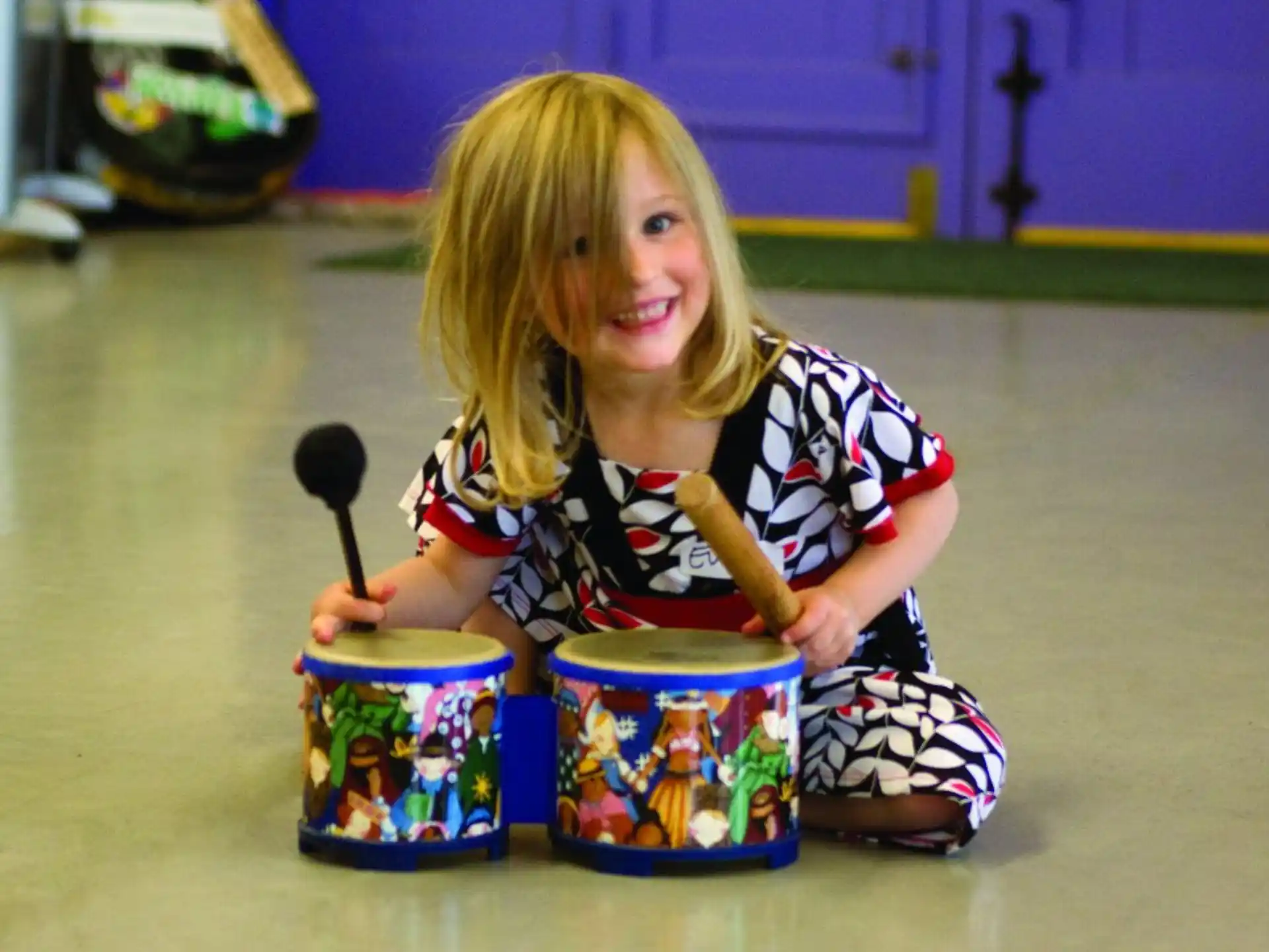 a girl sitting on the floor with a bucket of food