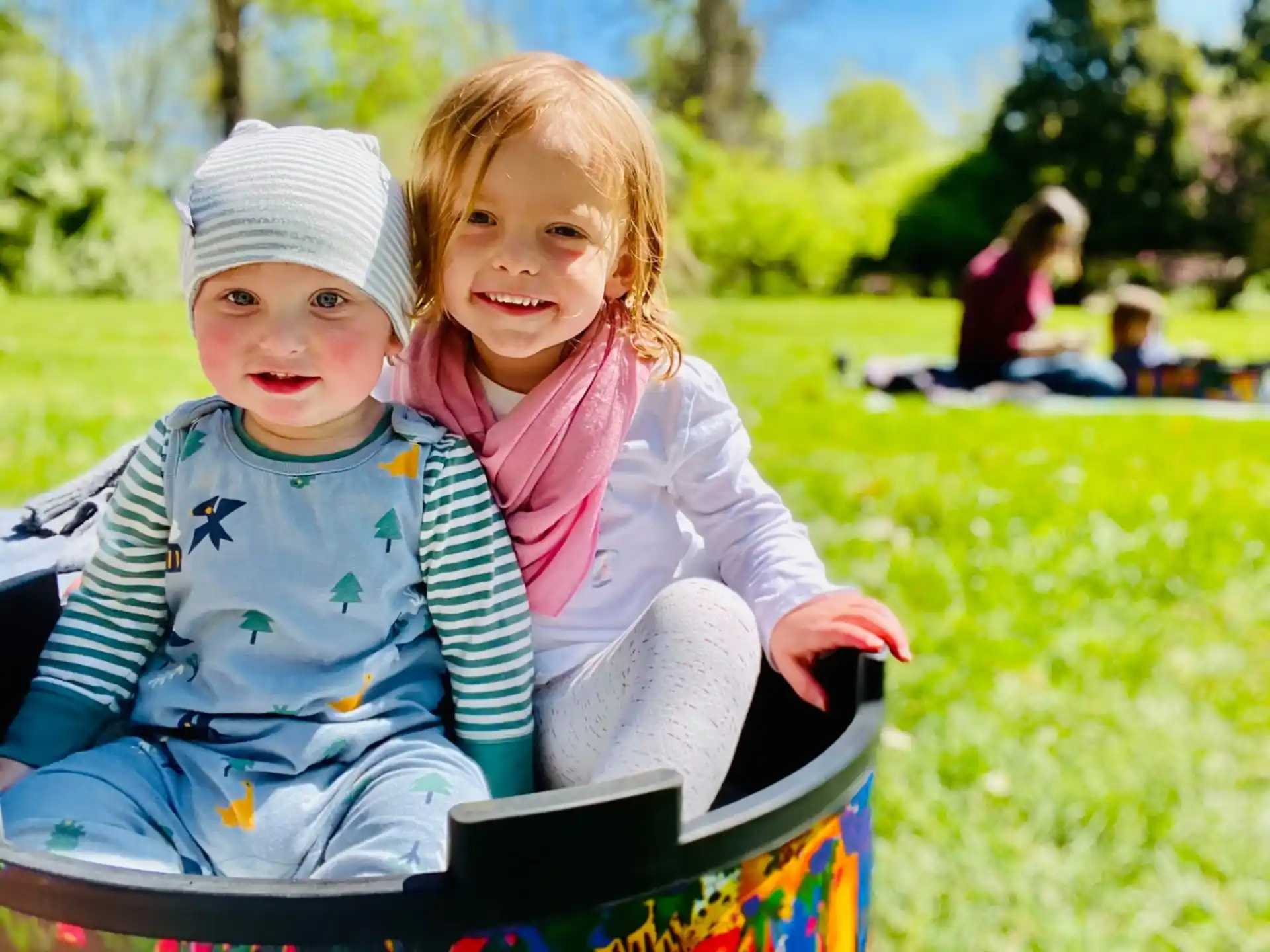 a couple of children sitting on a bench in a park