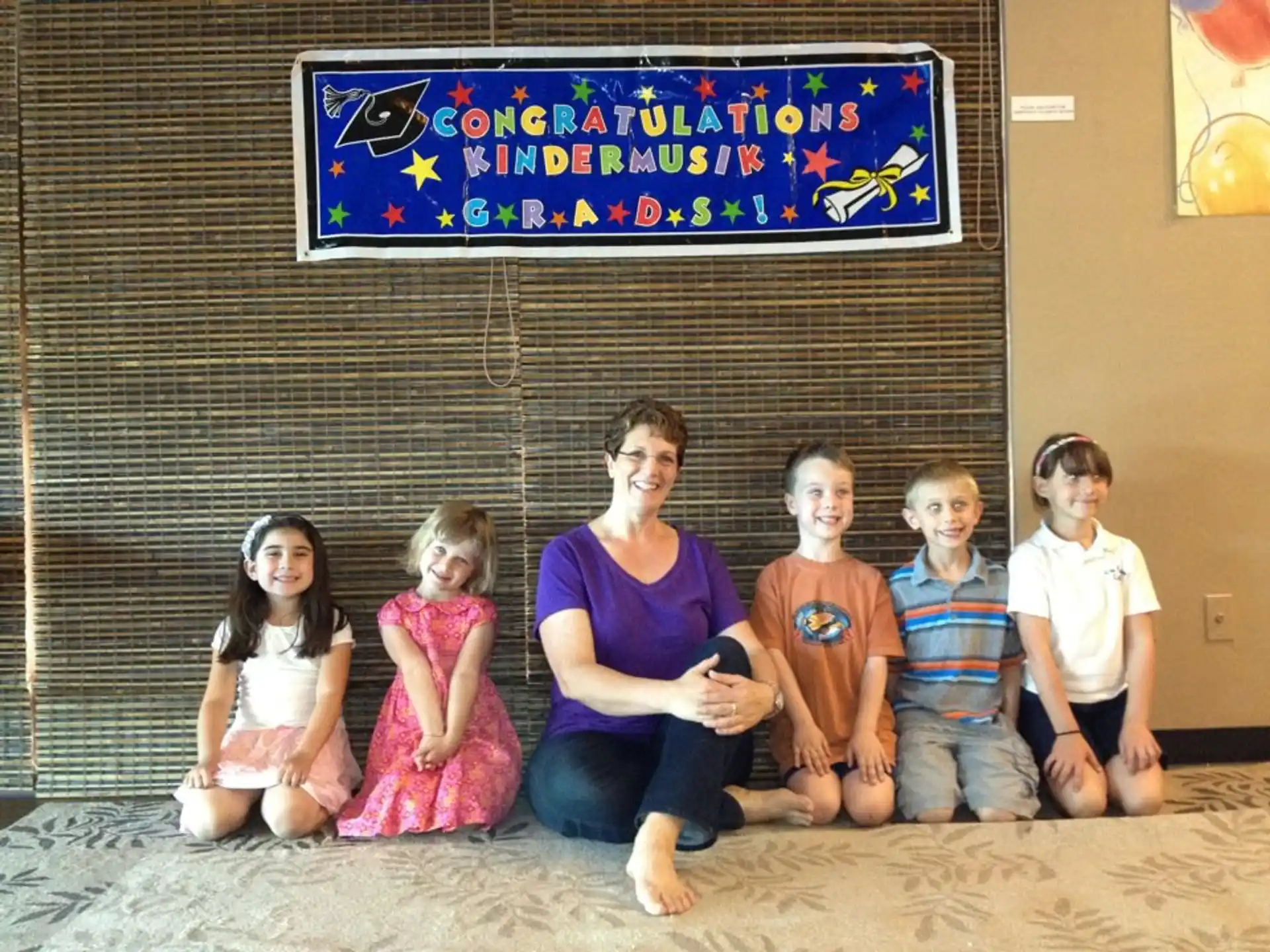 a group of children sitting on the floor in front of a sign