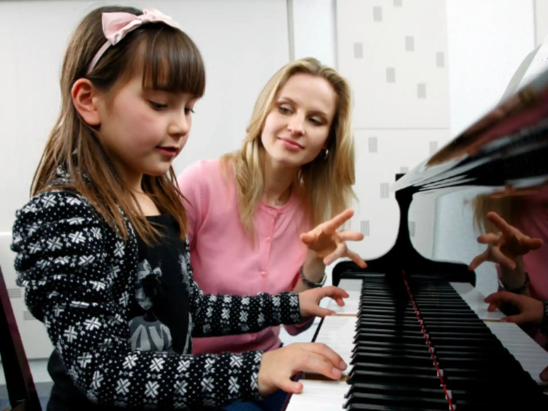 a couple of girls playing piano