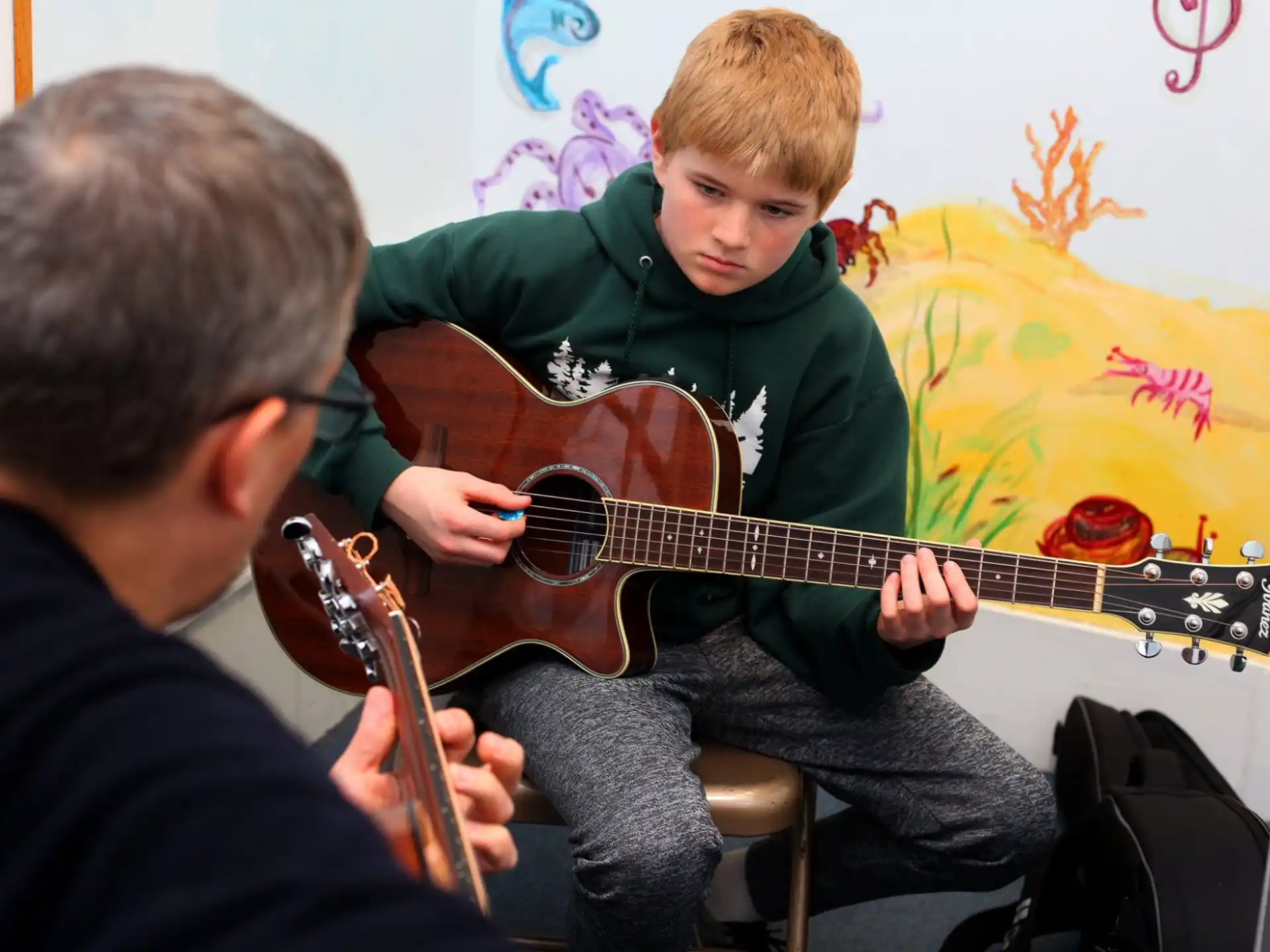 a man playing a guitar next to a boy
