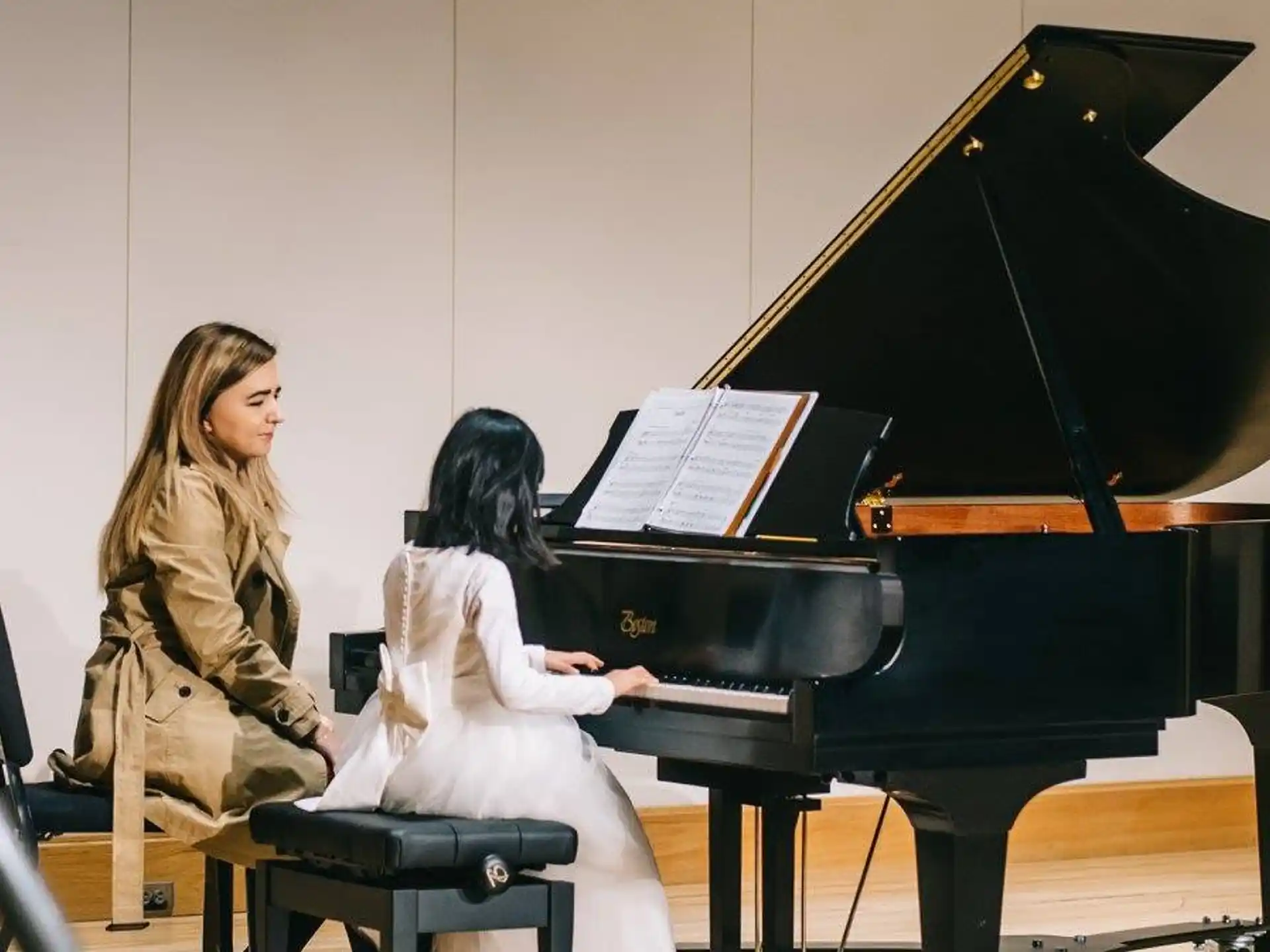 a person playing a piano with a young girl sitting on the side