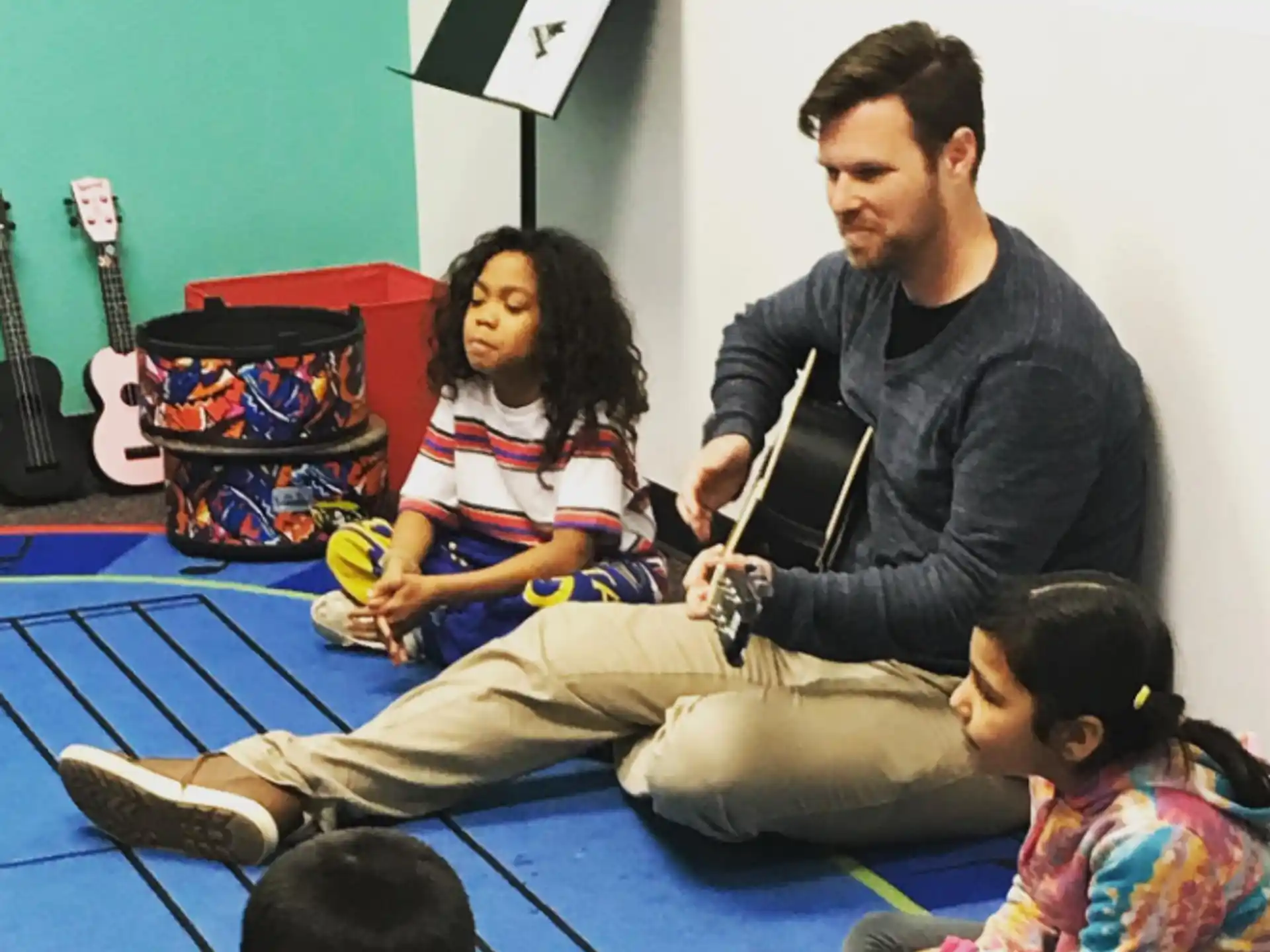 a man and a woman sitting on the floor with a group of children