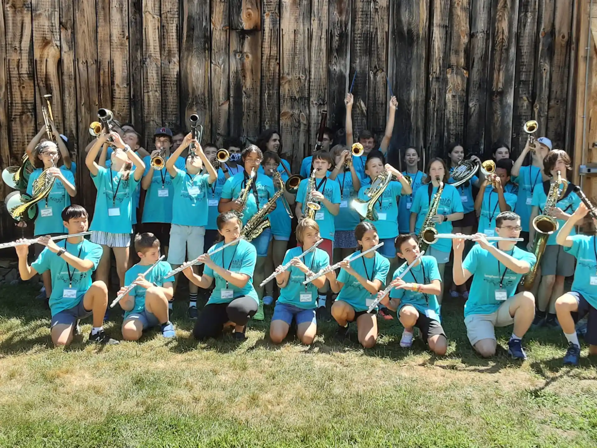 a group of people in blue uniforms holding swords in front of a wooden fence