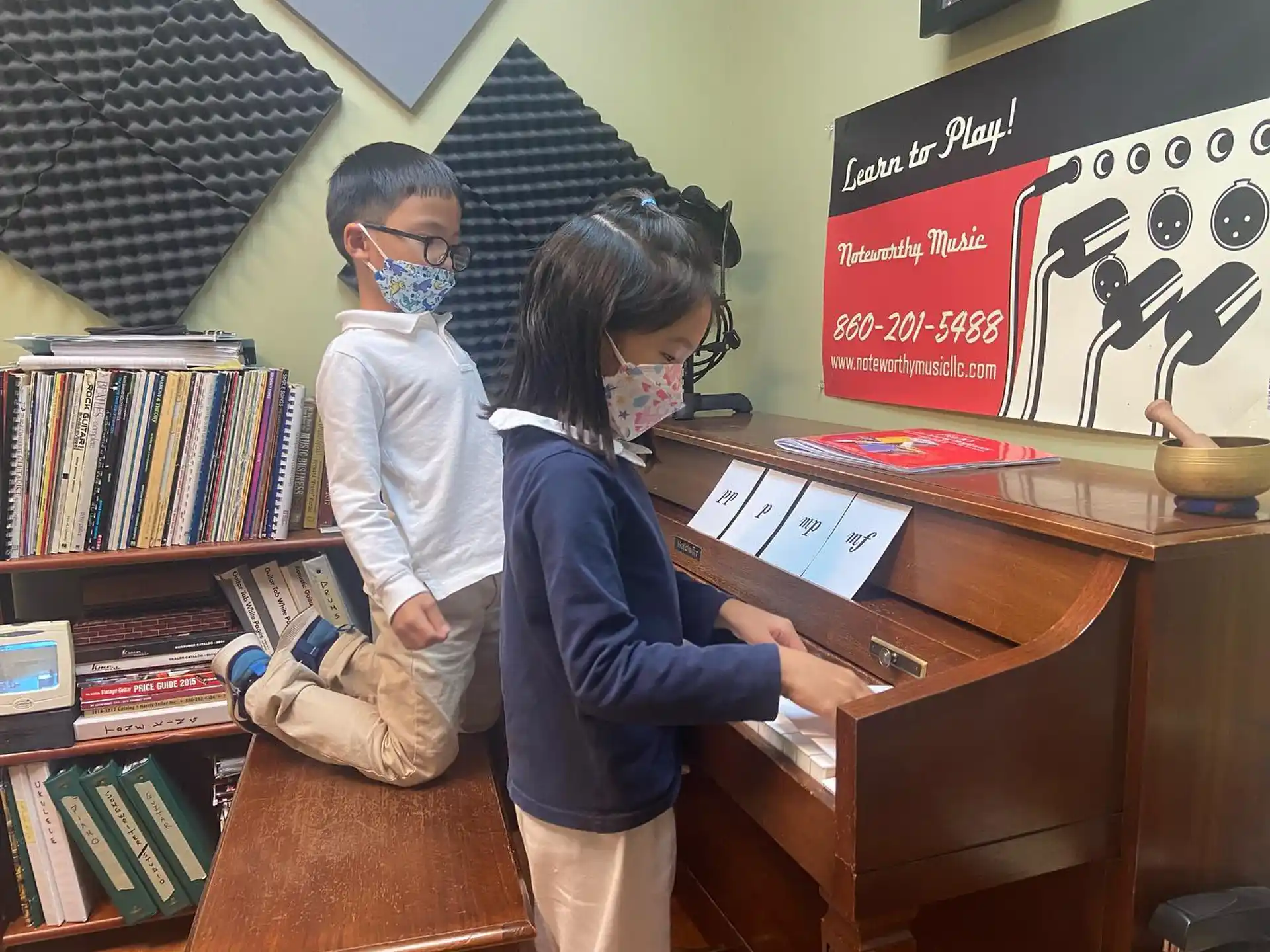 a person and a boy in a room with books and a piano