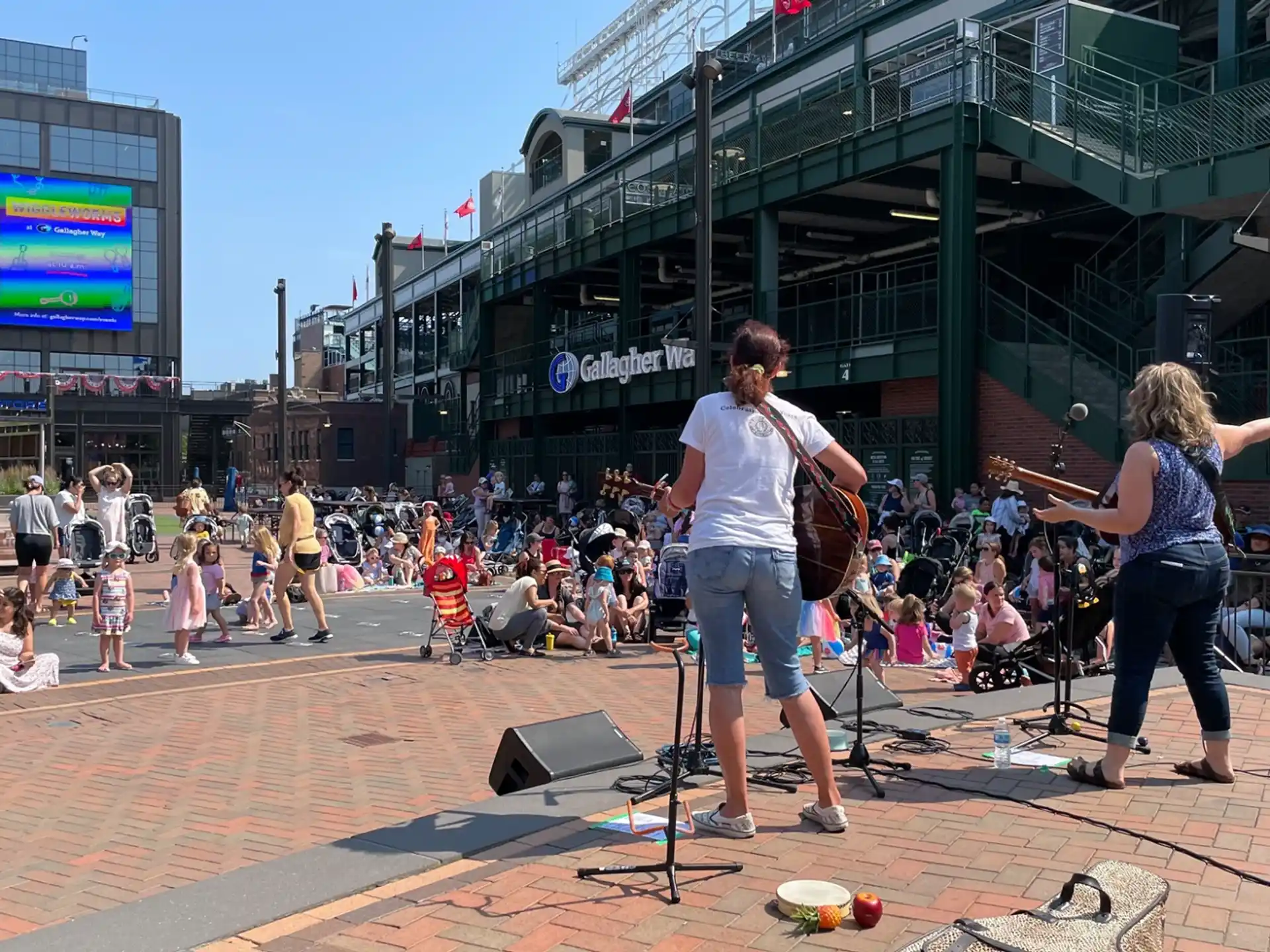a group of people playing instruments on a brick surface with a crowd watching