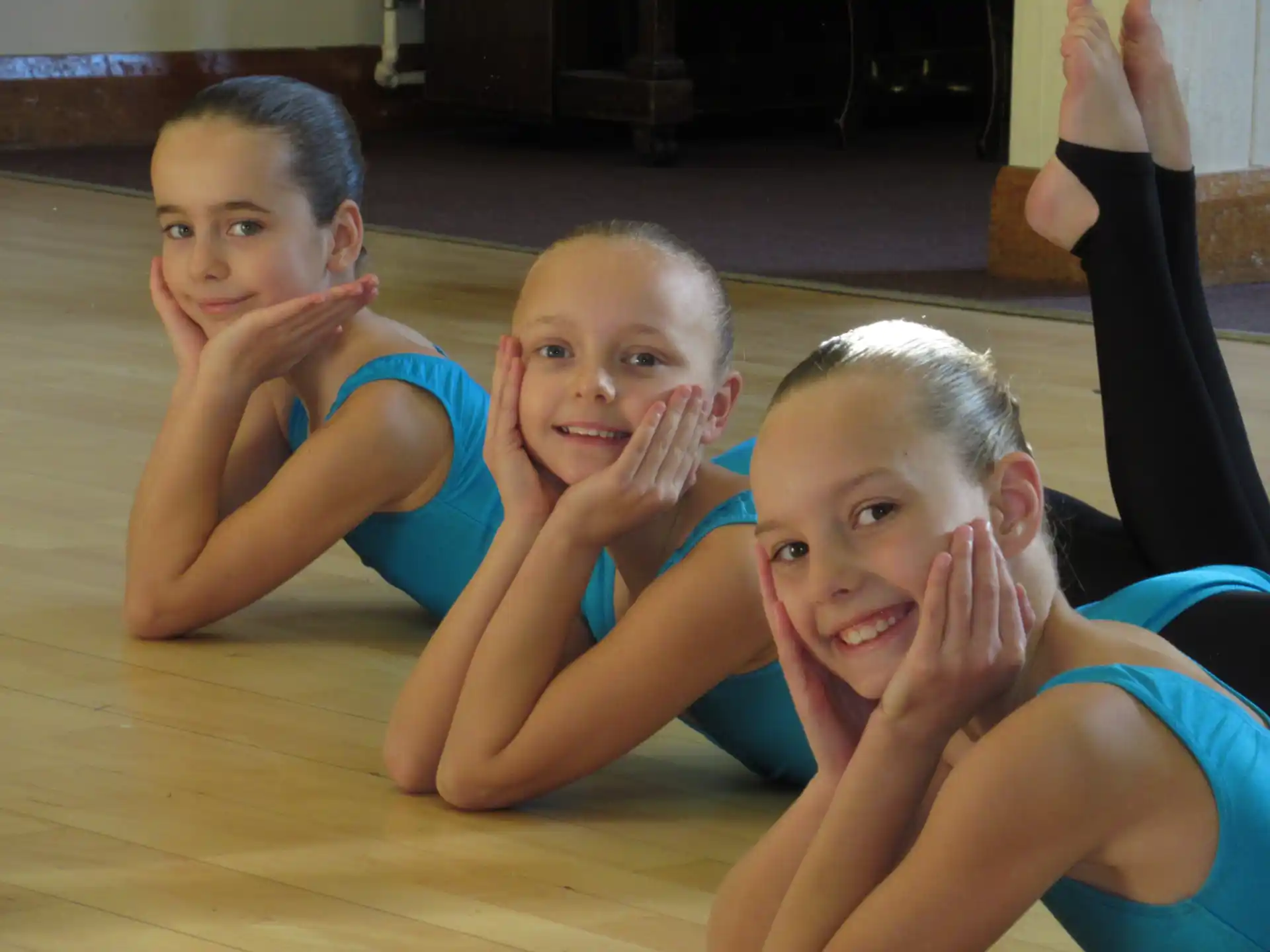 a group of girls in blue swimsuits on a wood floor