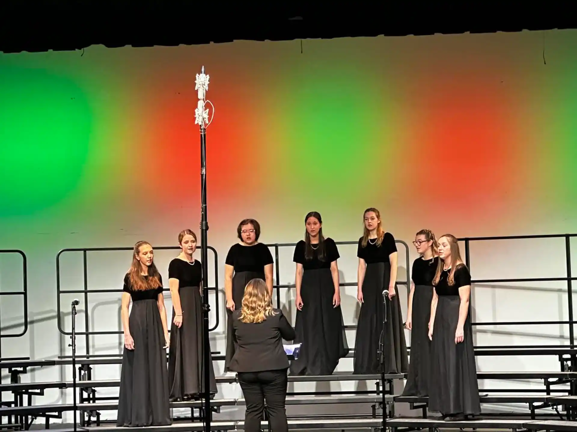a group of people standing on a stage with a bright light behind them