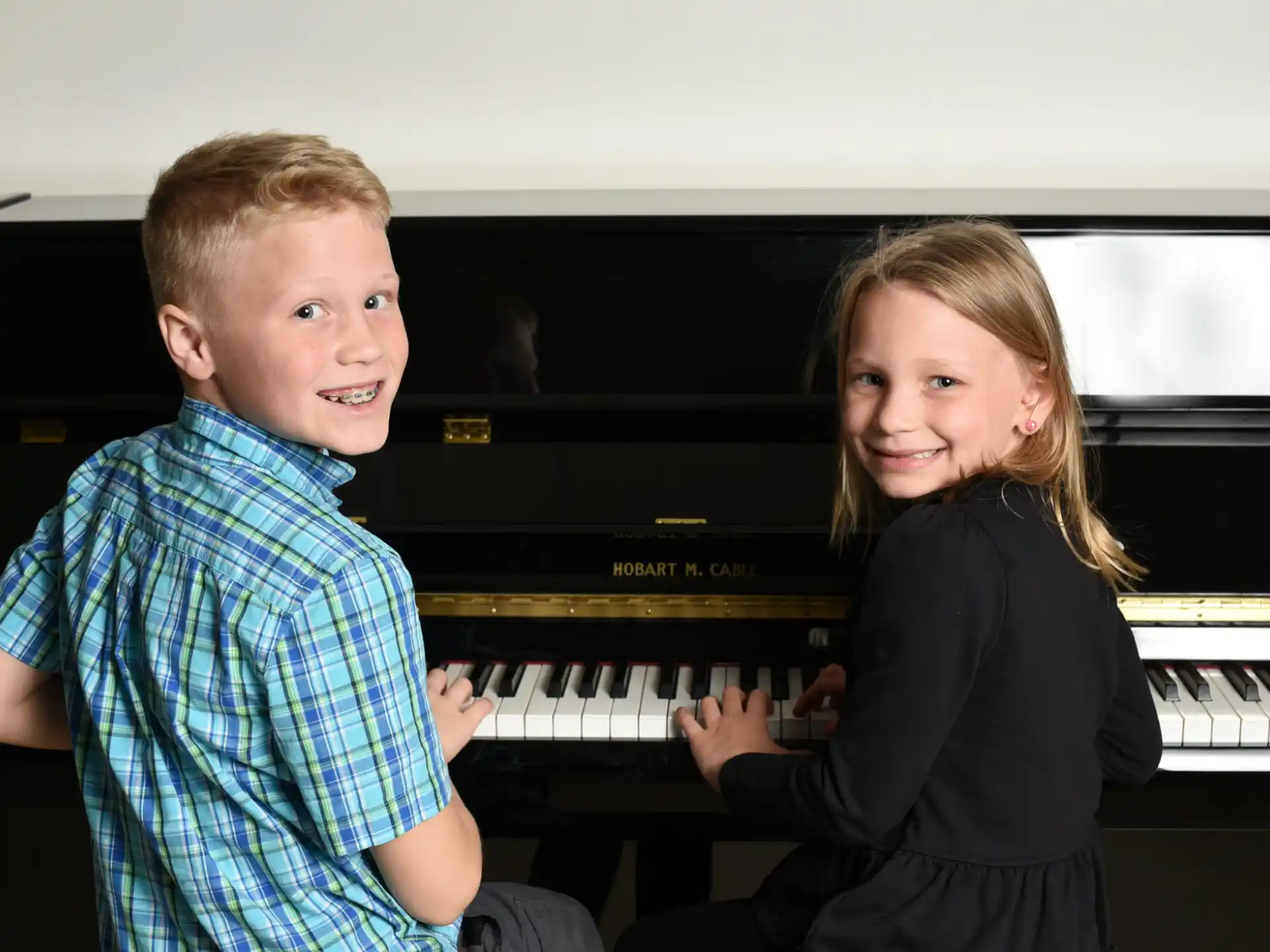 a boy and girl playing a piano