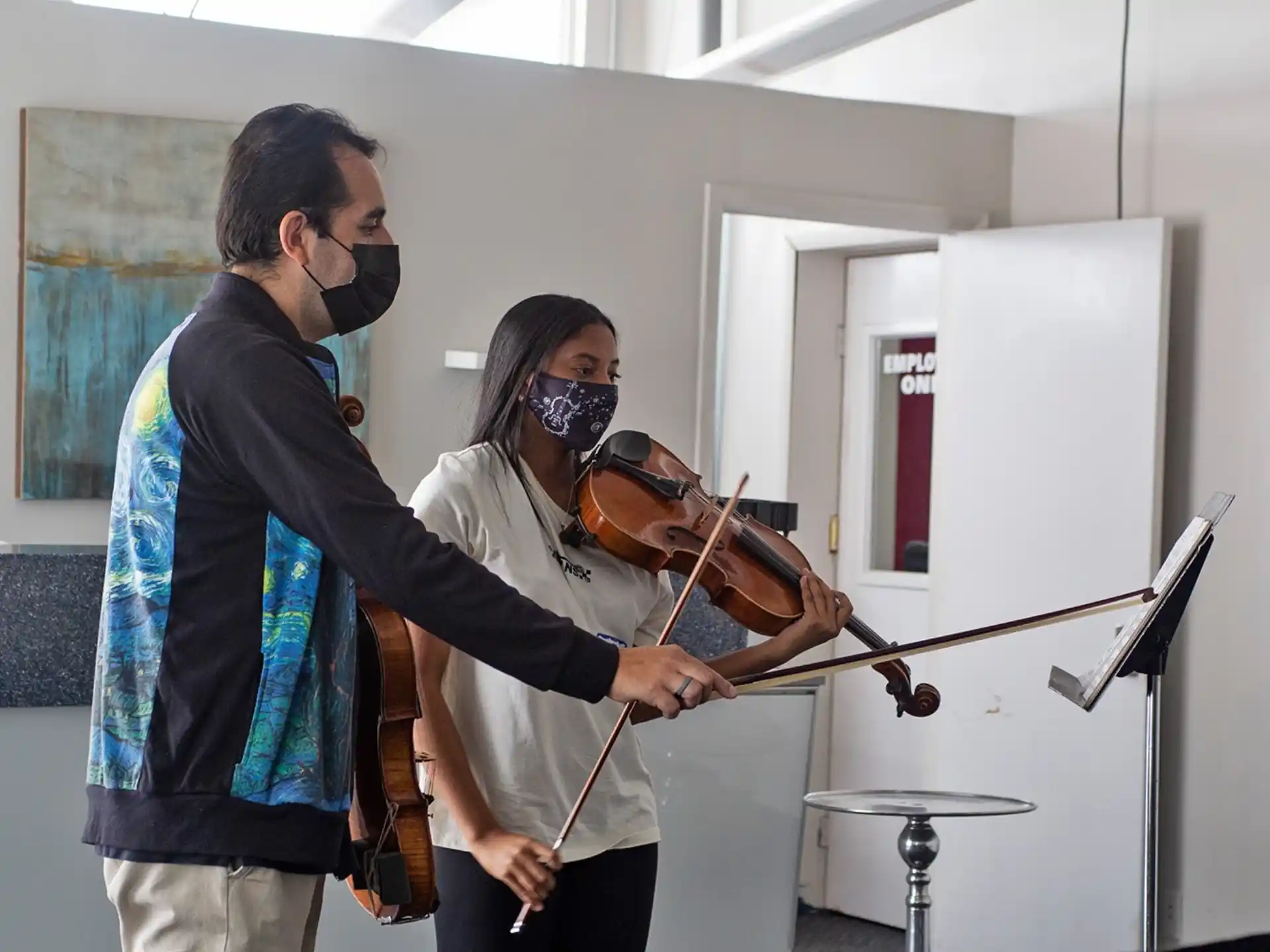 a person playing a violin next to a person with a mask