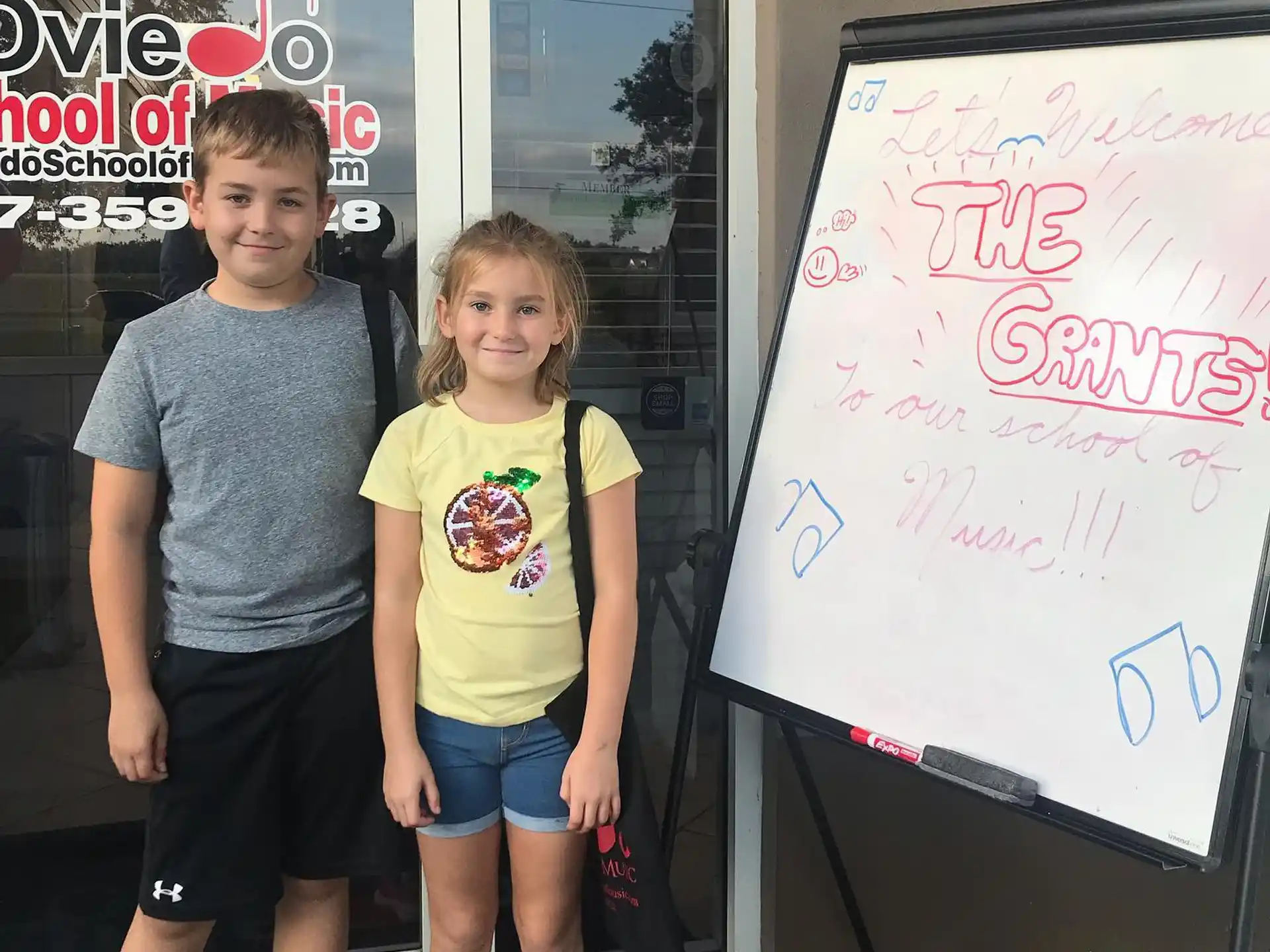 a boy and girl standing next to a sign