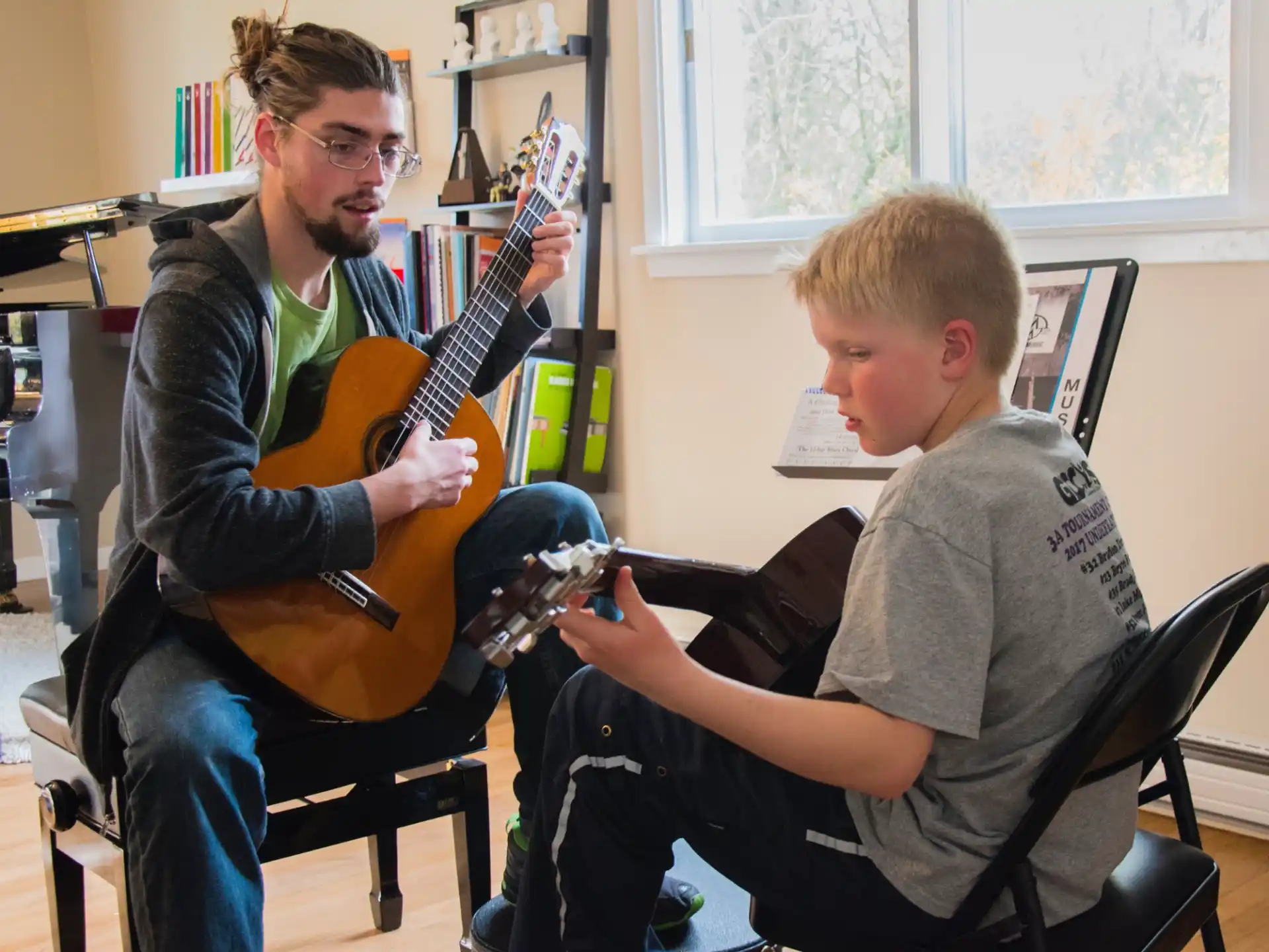 a person playing a guitar next to a boy sitting in a chair