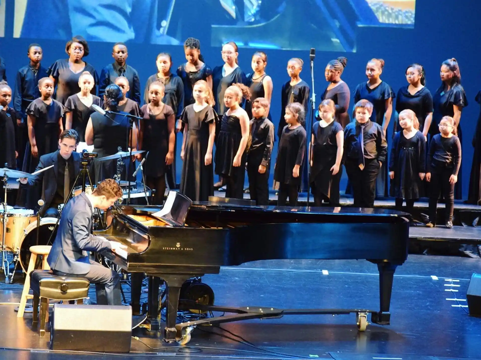 a group of people standing behind a piano