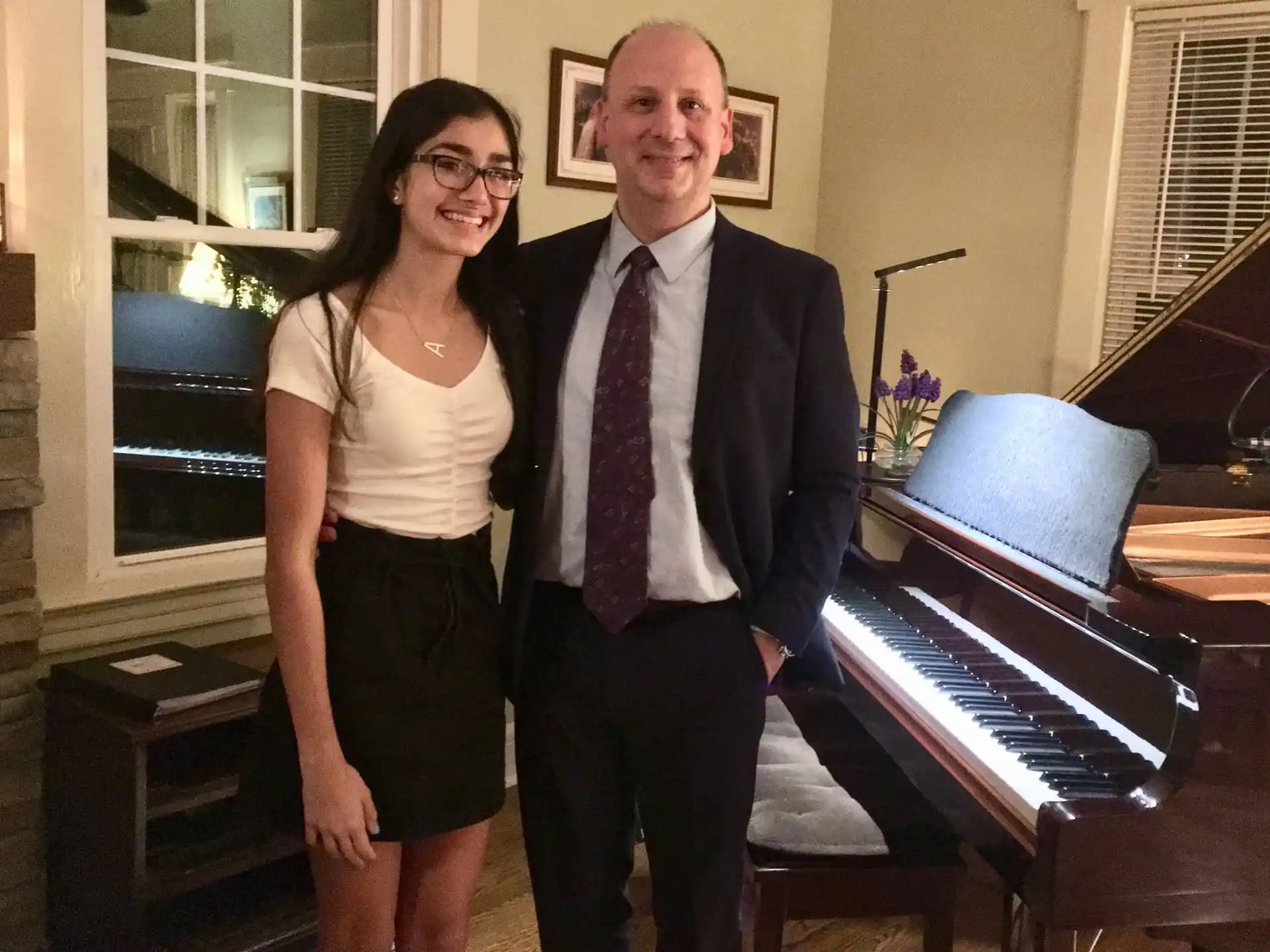 a man and a woman standing next to a piano