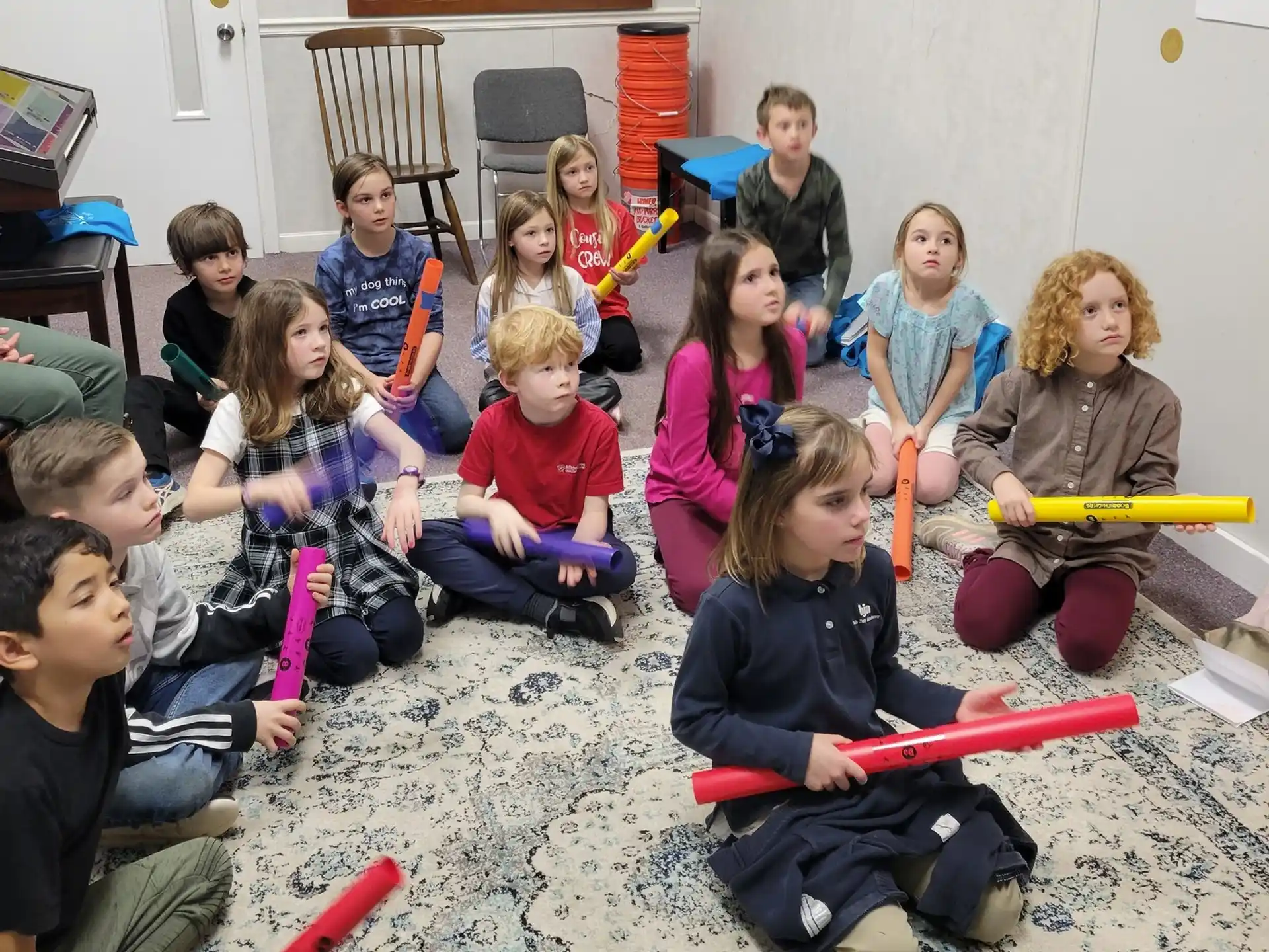 a group of children sitting on the floor holding toy bats