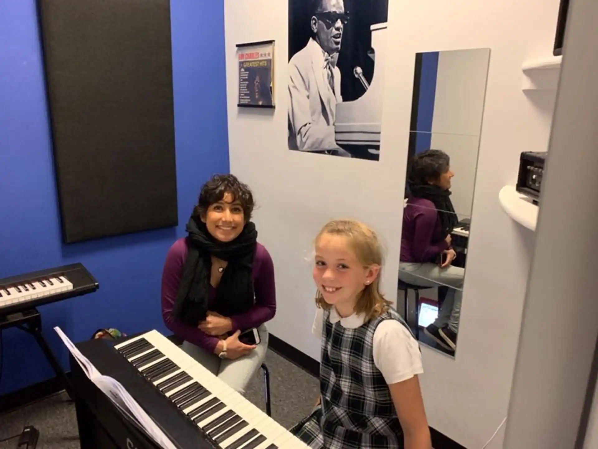 a couple of girls sitting at a piano