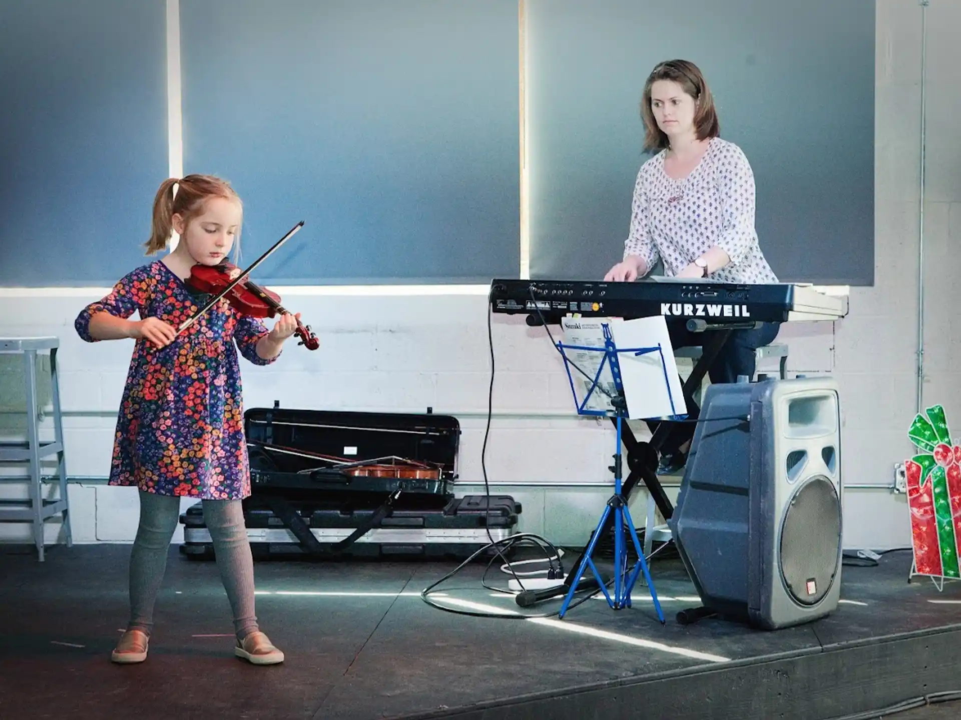 a girl playing the violin next to a person playing the piano