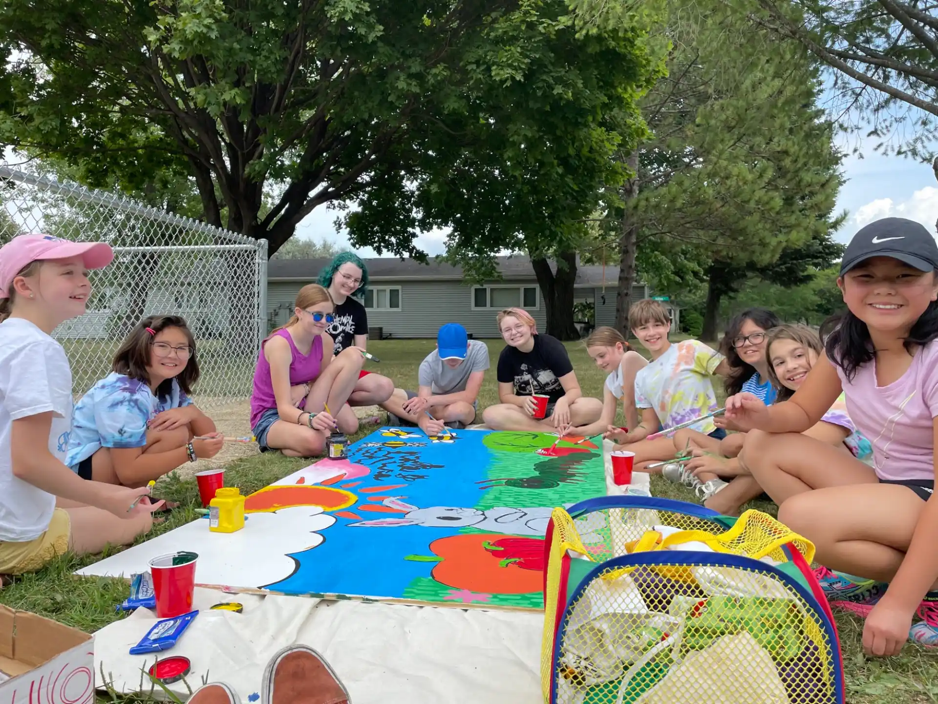 a group of people sitting on a blanket in a grassy area
