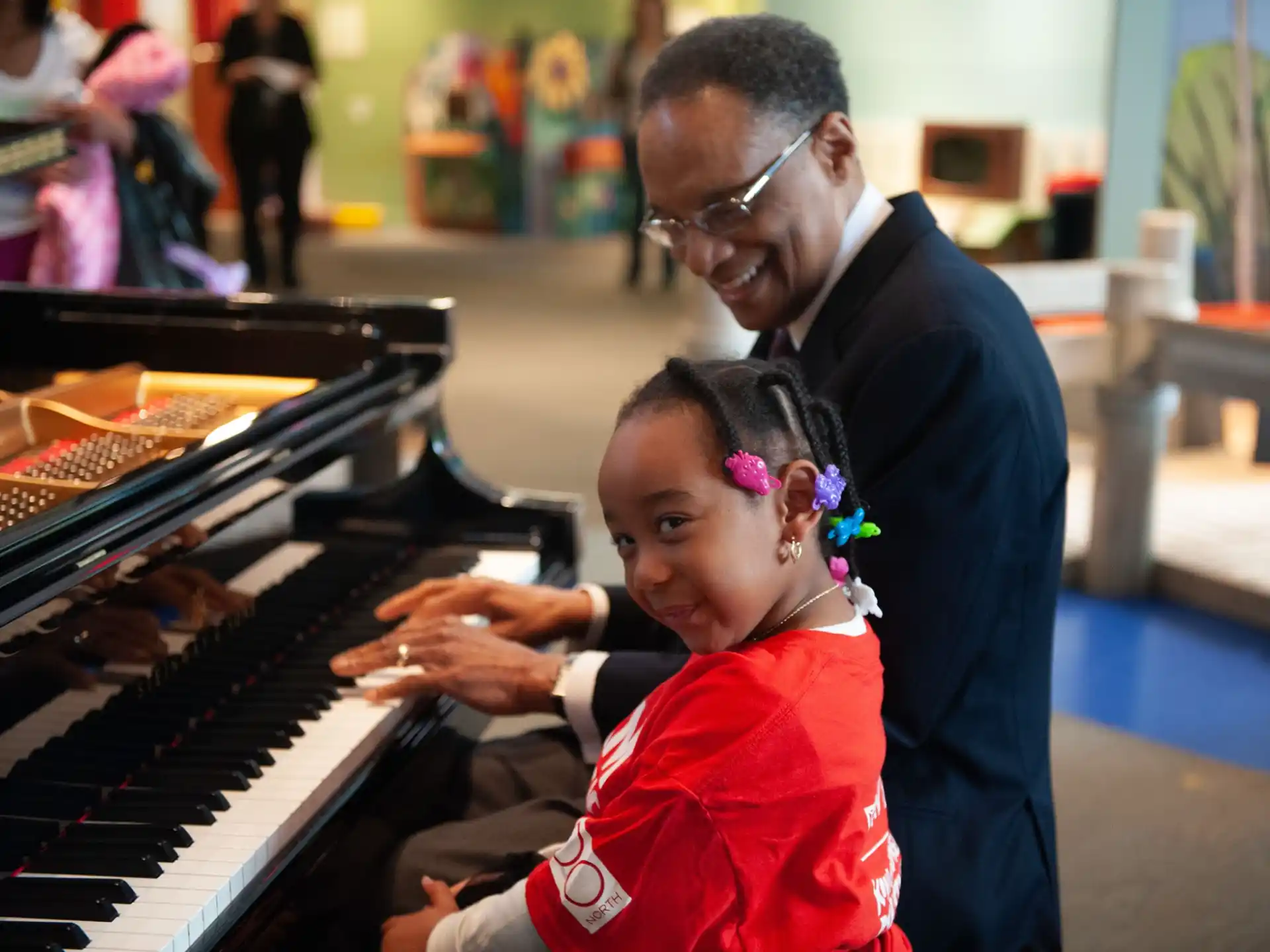 a person and a child playing a piano