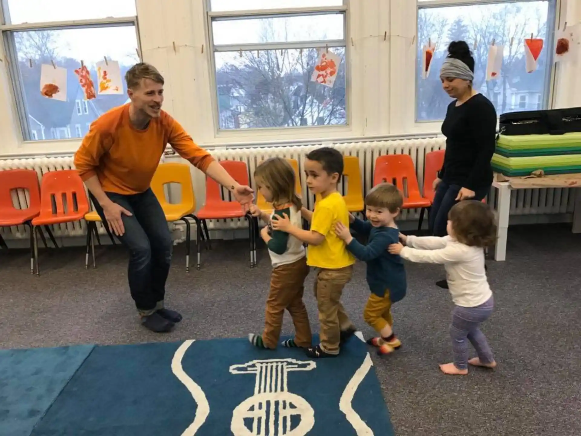 a group of people standing around a person sitting at a table with children