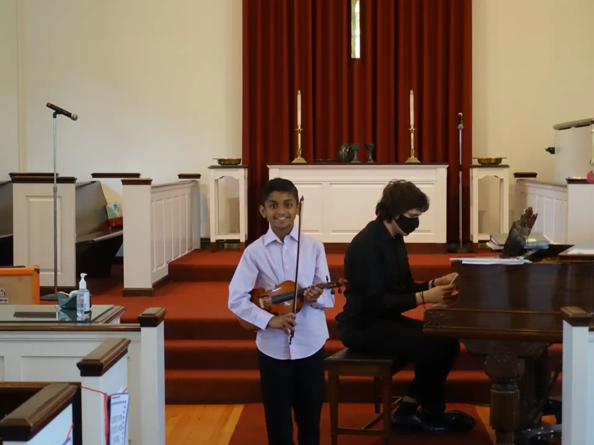 a man playing a violin next to a woman sitting at a desk