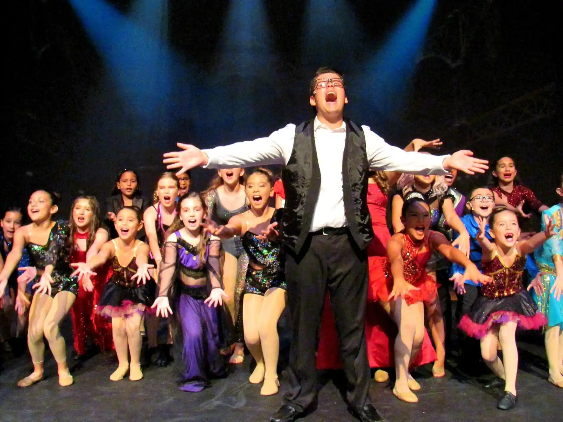 a man in a suit dancing with a group of children