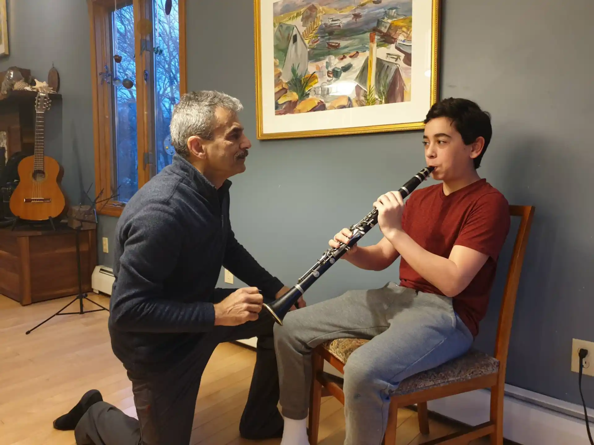 a person playing a guitar next to a person sitting in a chair