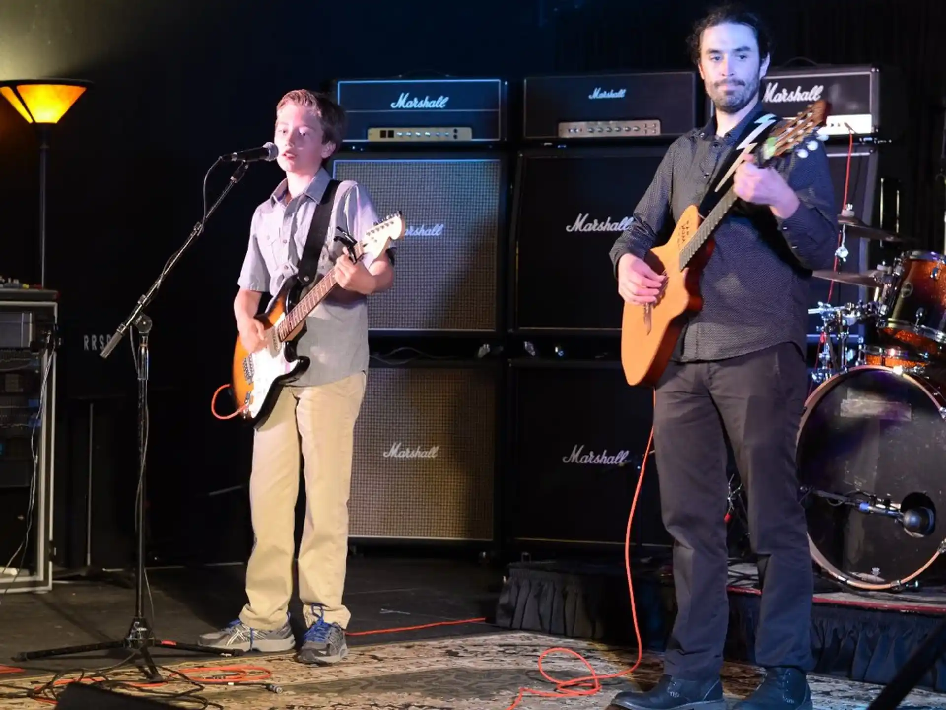a couple of men playing guitars on a stage