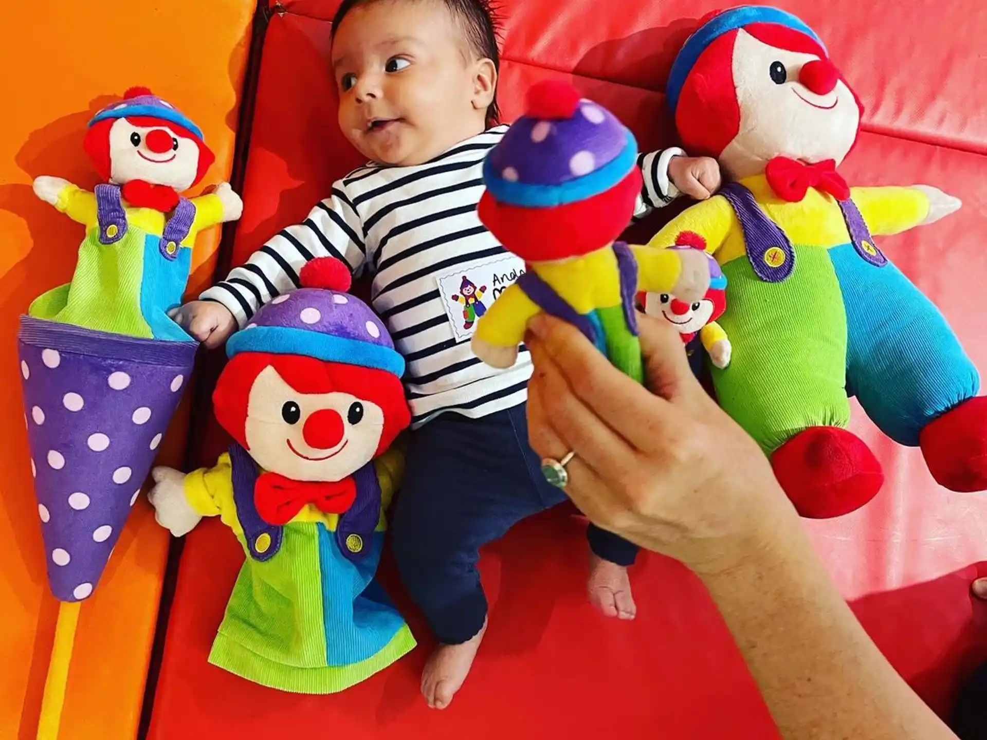 a boy sitting on a red slide with many stuffed toys