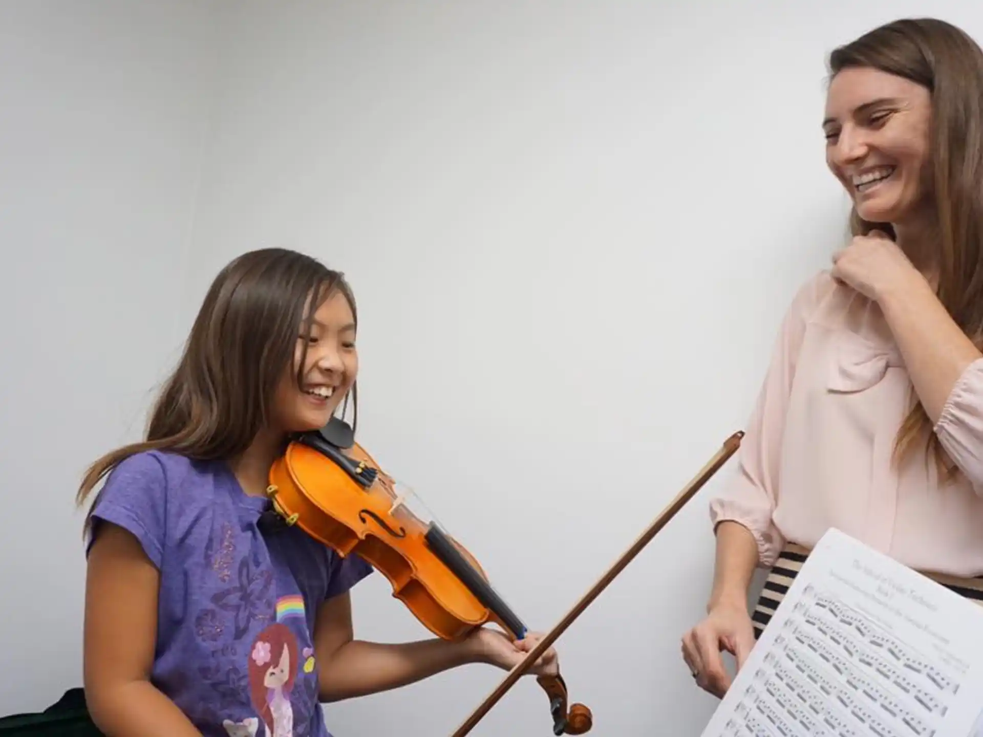 a woman playing a violin next to a girl playing a violin
