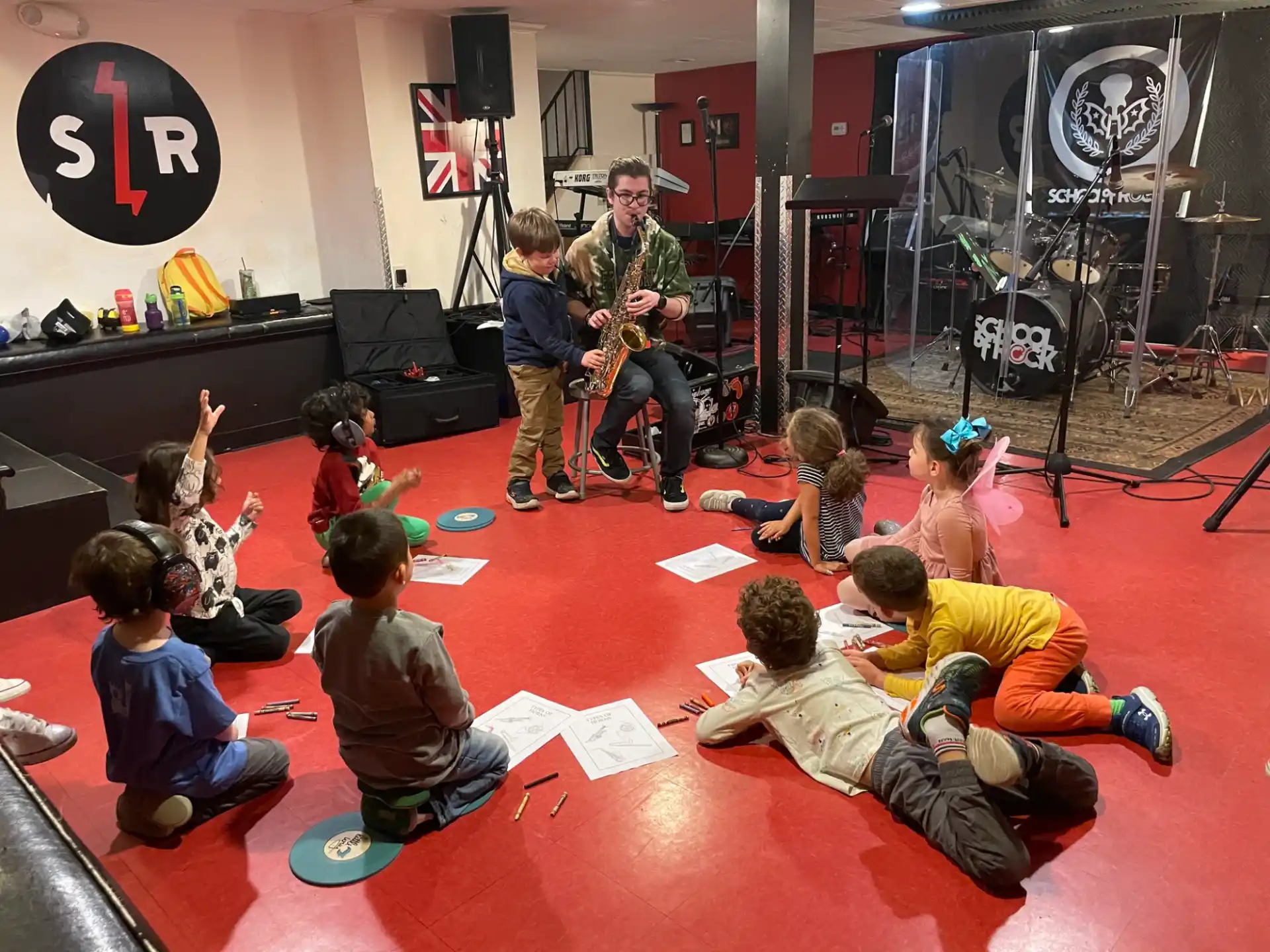 a group of people sitting on the floor with a person playing guitar