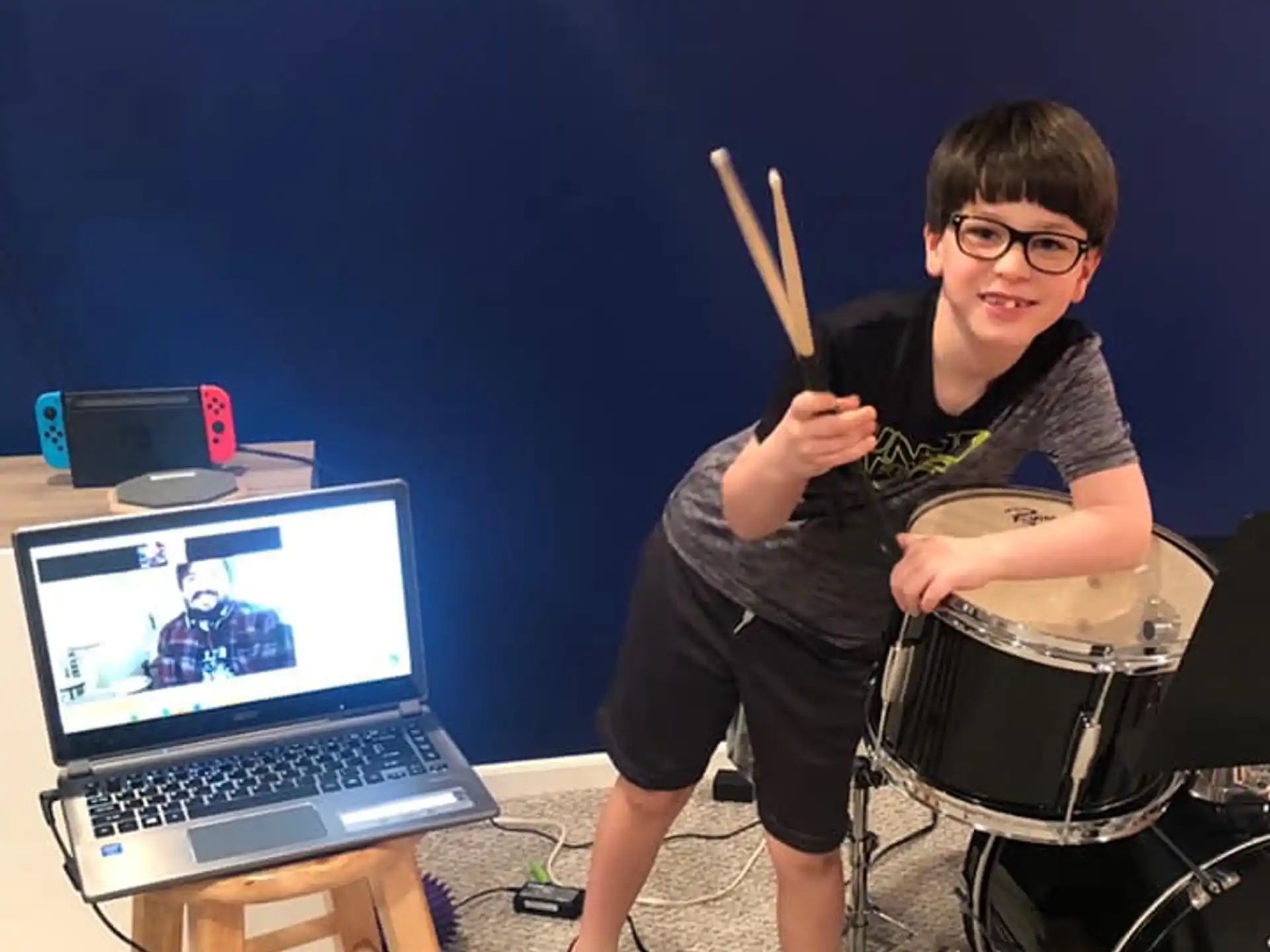 a boy sitting in a chair with a laptop and a table with a computer