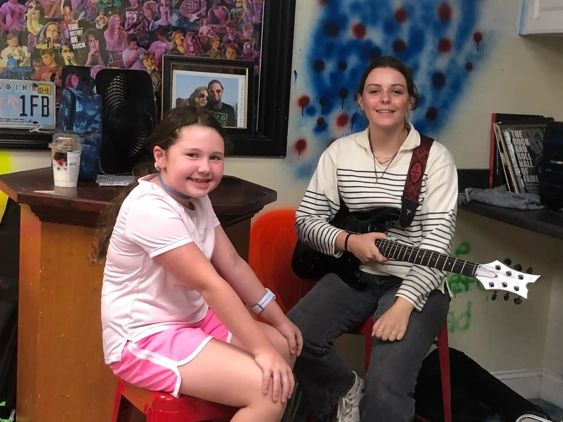 a woman and a girl sitting on a stool and holding a guitar