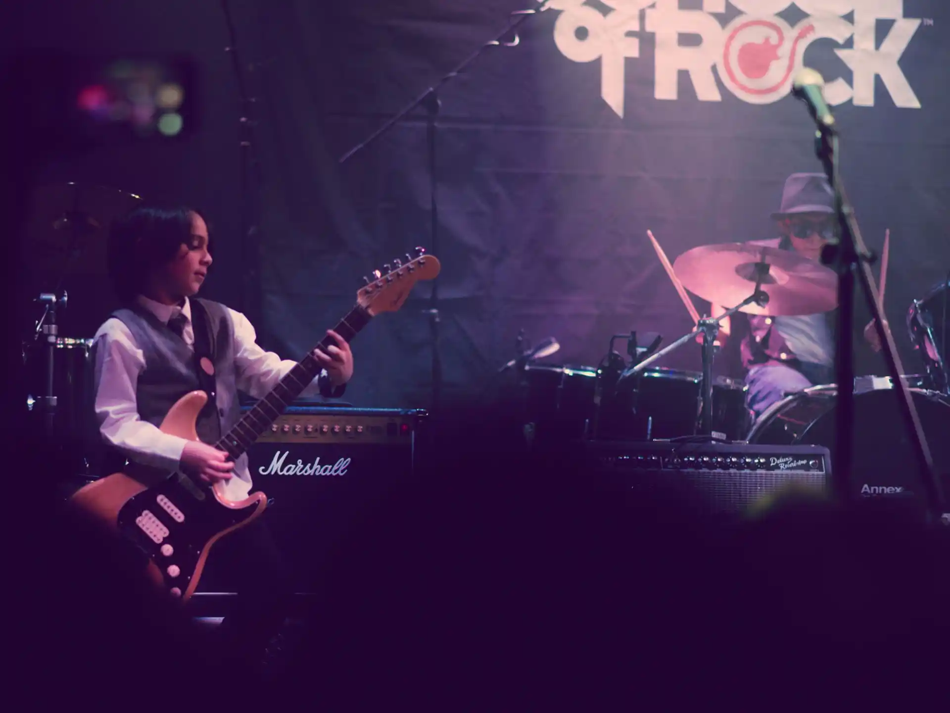 a person playing a guitar on a stage with a band playing