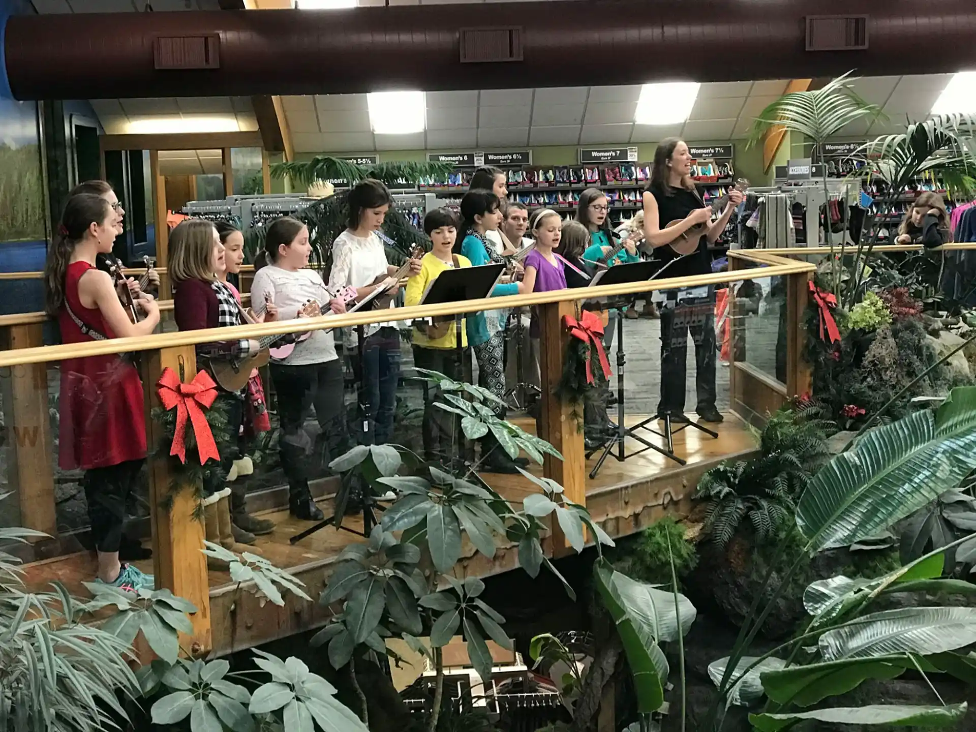a group of people standing in a room with plants and a stage