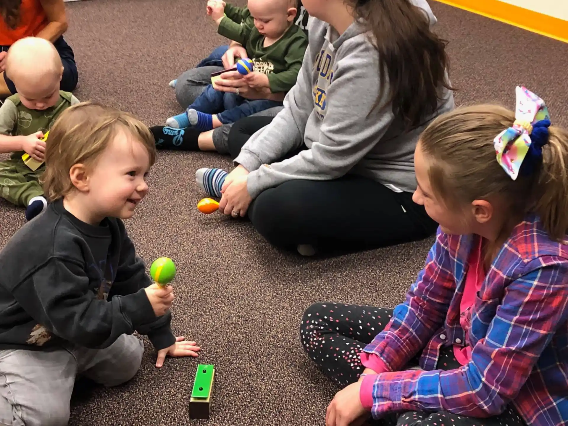 a group of children sitting on the ground playing with toys