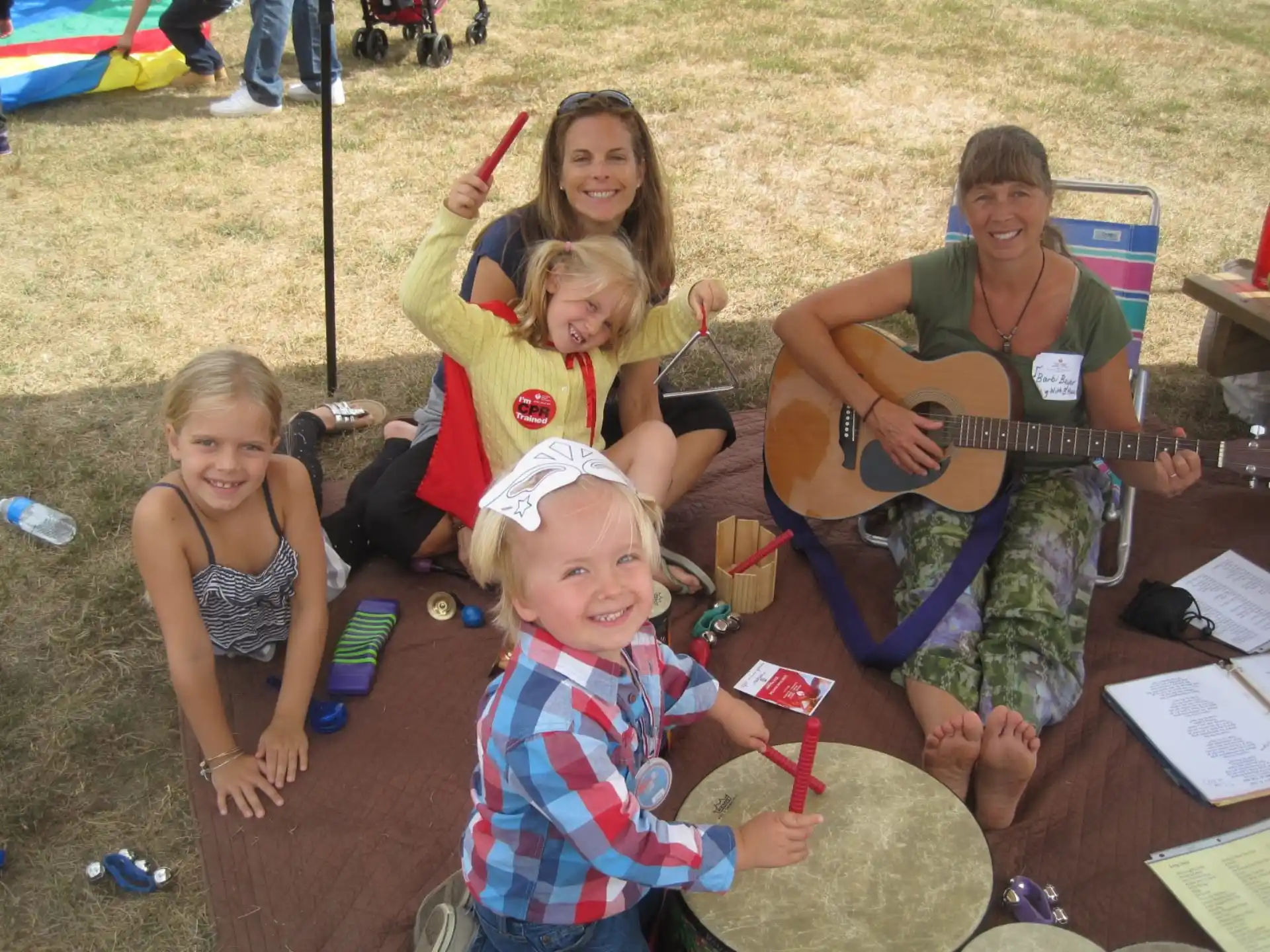 a group of children sitting on the ground playing instruments
