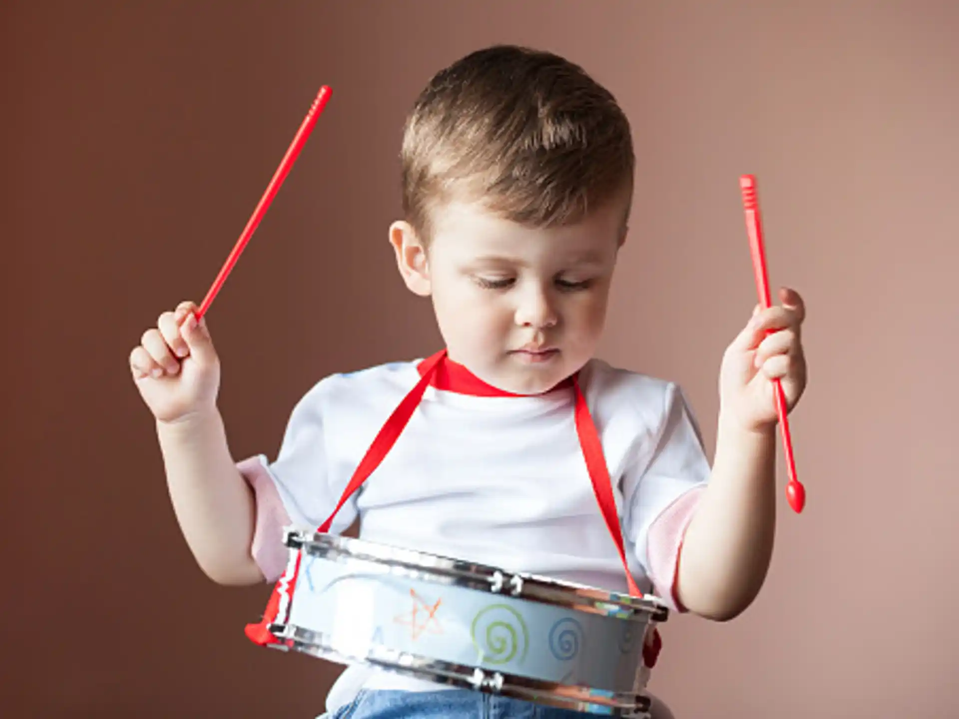 a young boy holding a red and white pencil