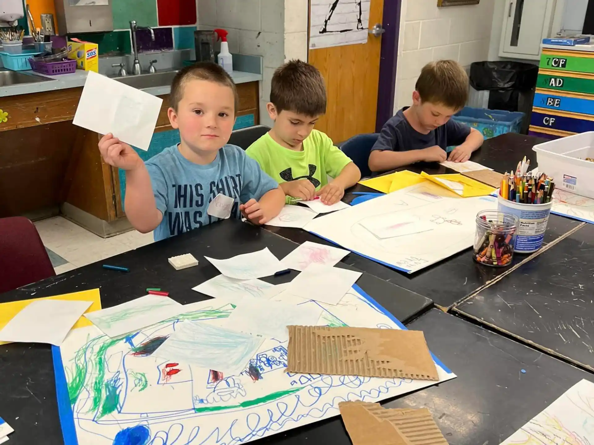 a group of children sitting at a table with papers and pencils