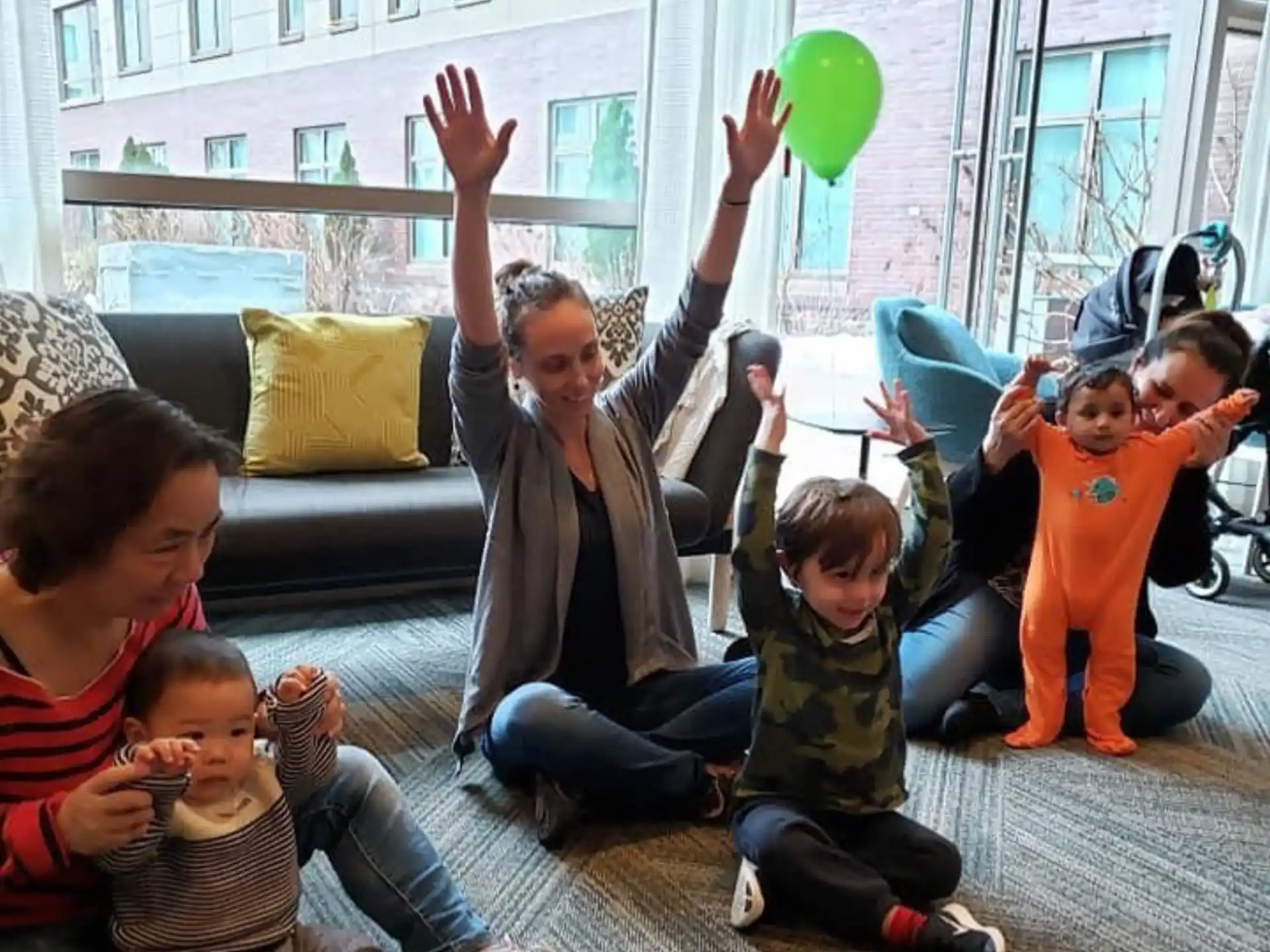 a group of people sitting on the ground with a green balloon
