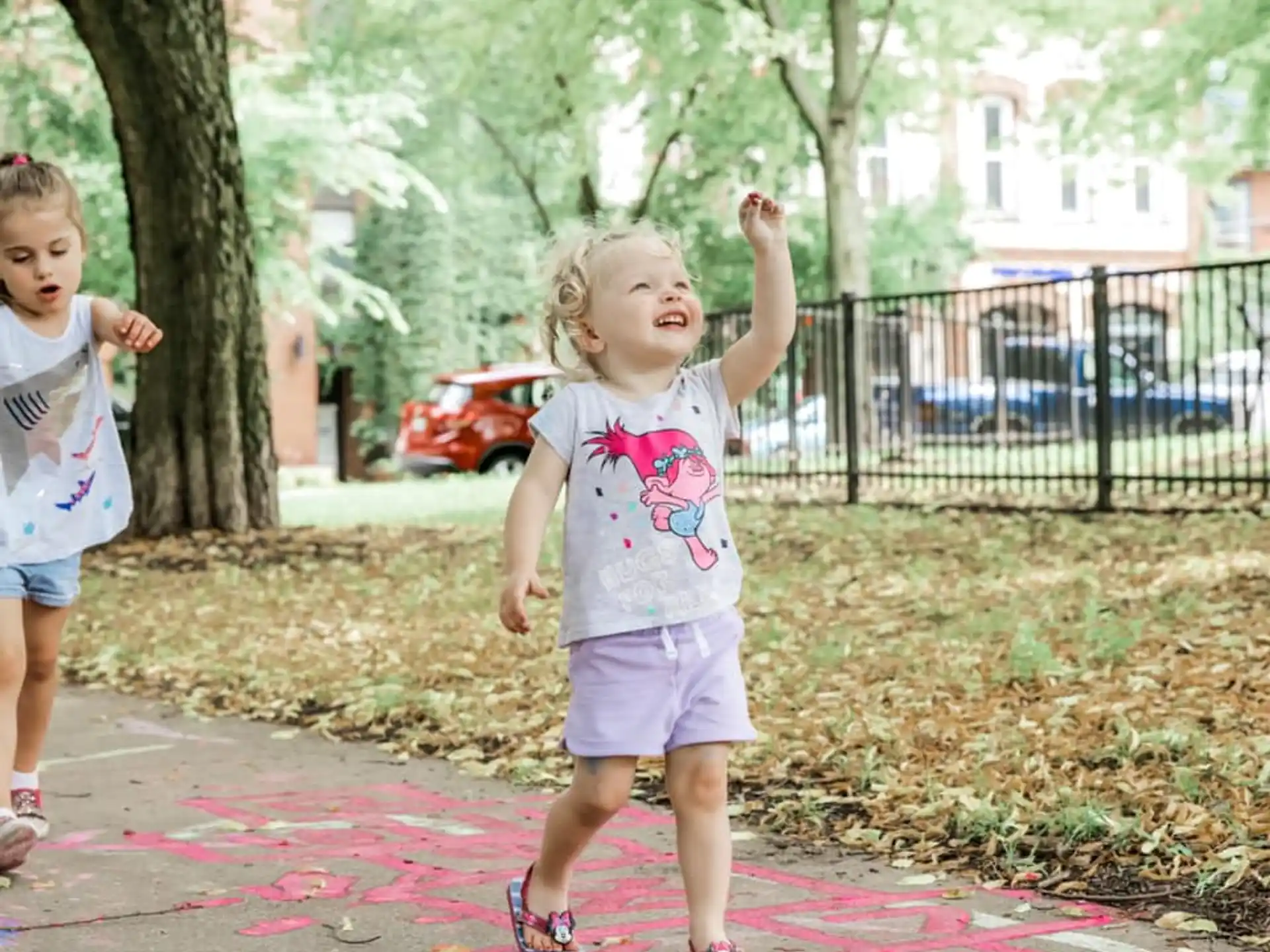 a couple of children running on a sidewalk