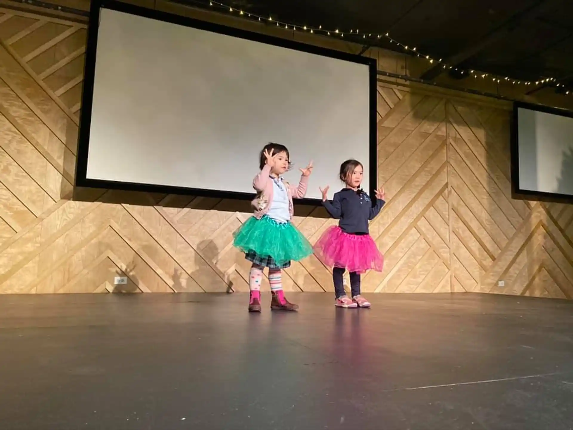 a boy and girl dancing on a stage in front of a screen