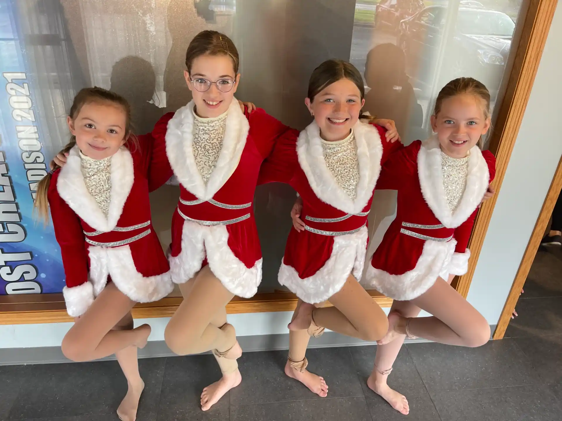 a group of children in red and white clothing sitting on a bench
