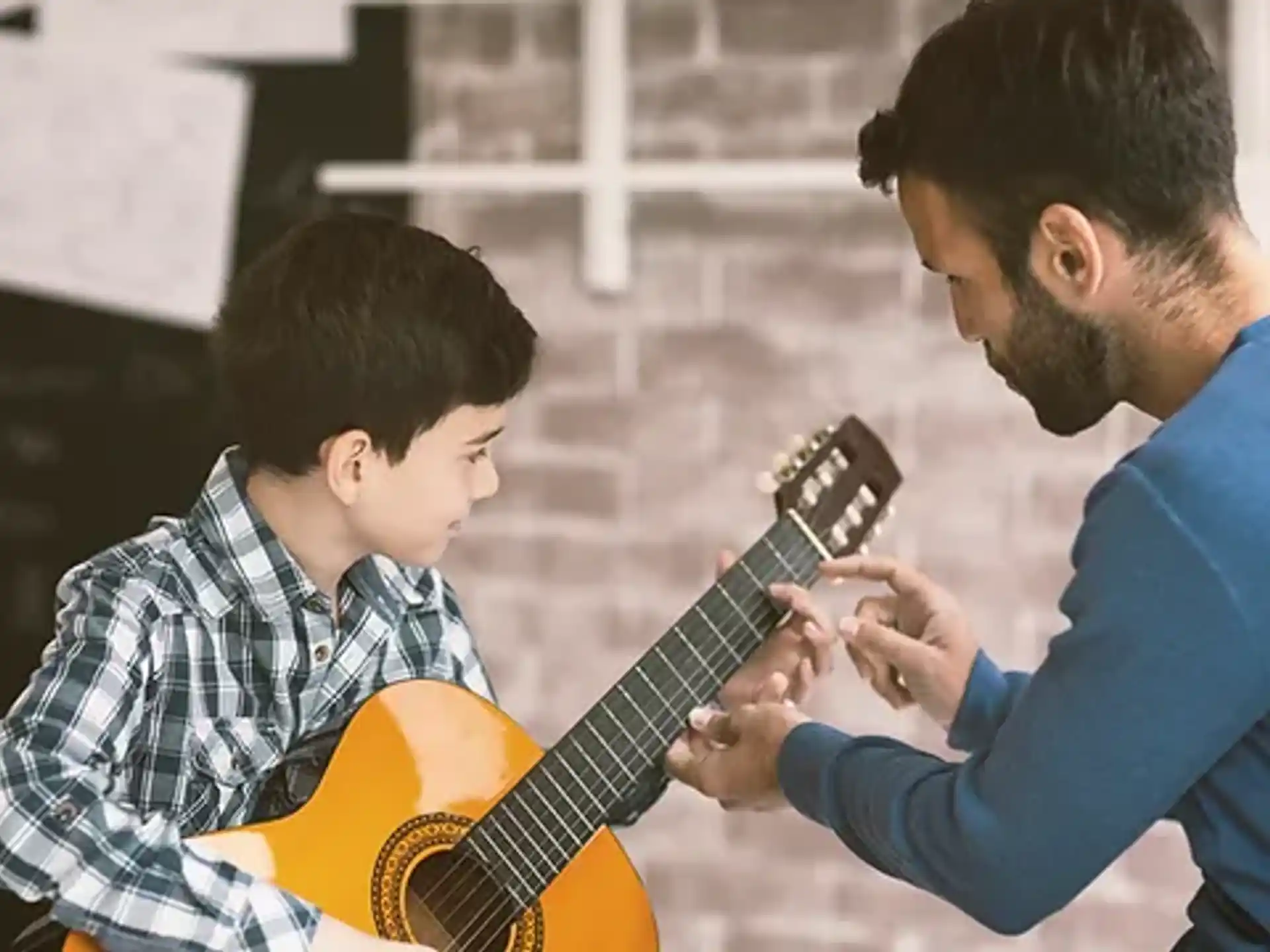 a man playing a guitar to a young boy