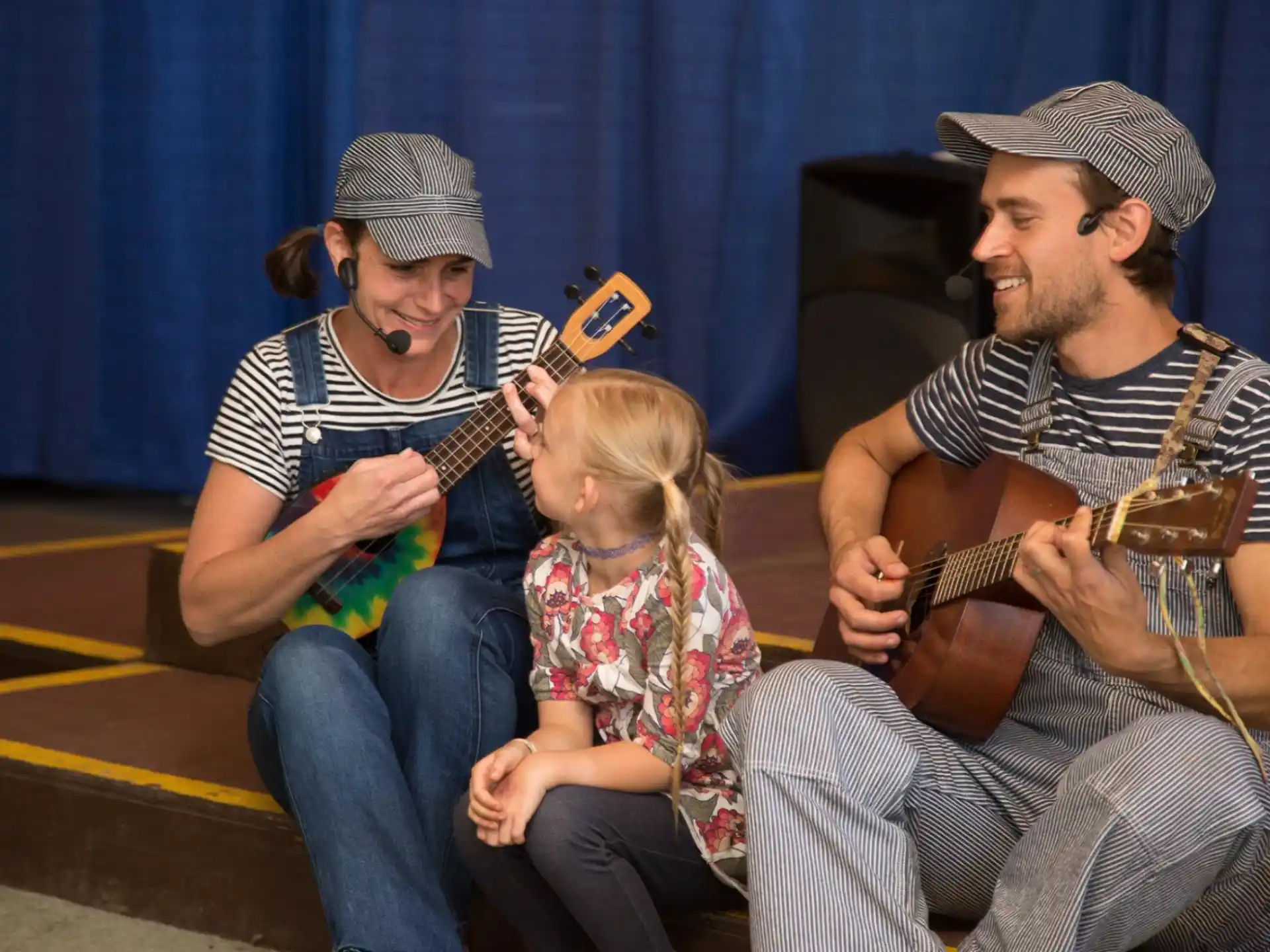 a man and woman playing guitar with a little girl