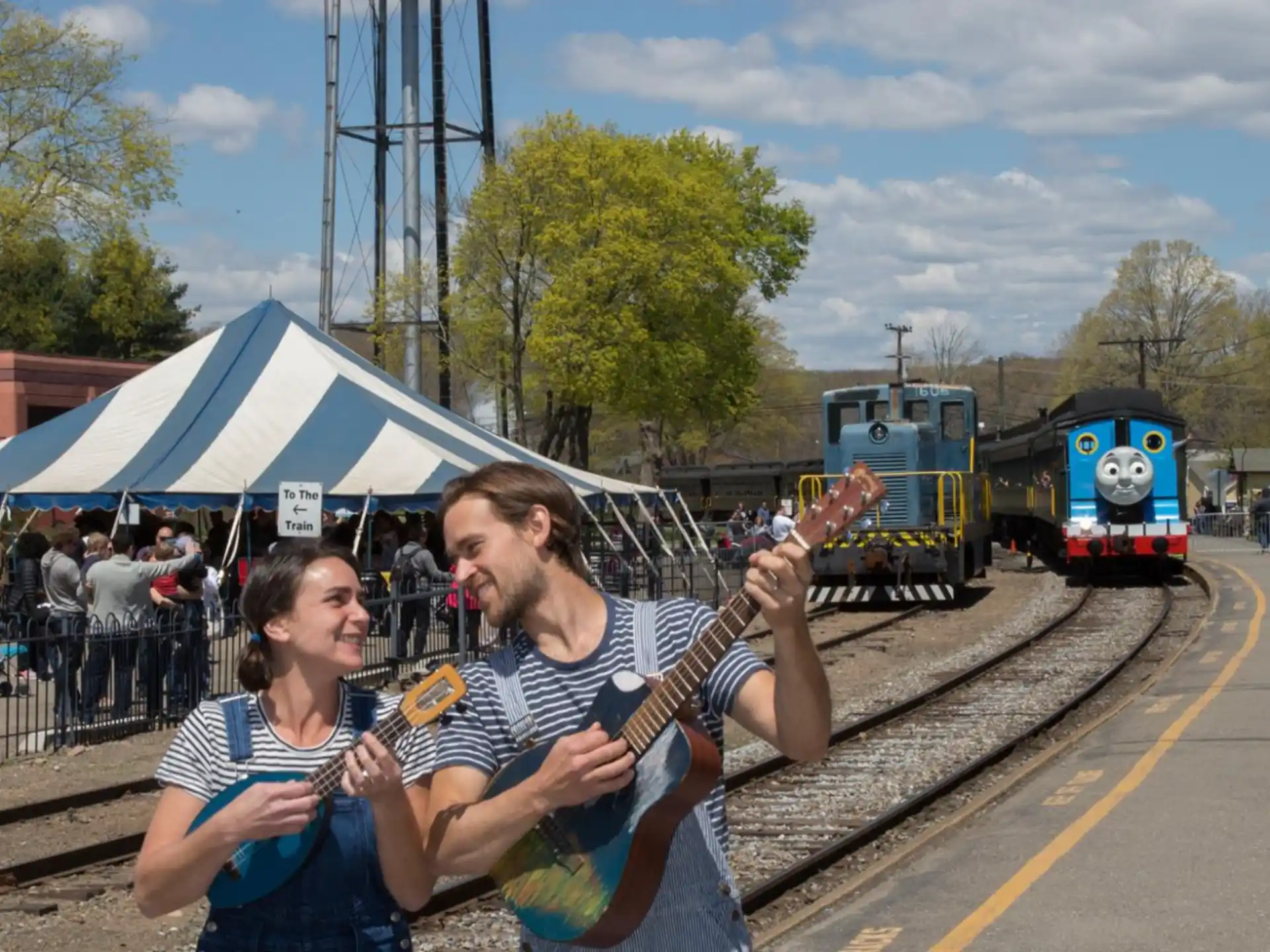 a man playing guitar next to a woman on a train track
