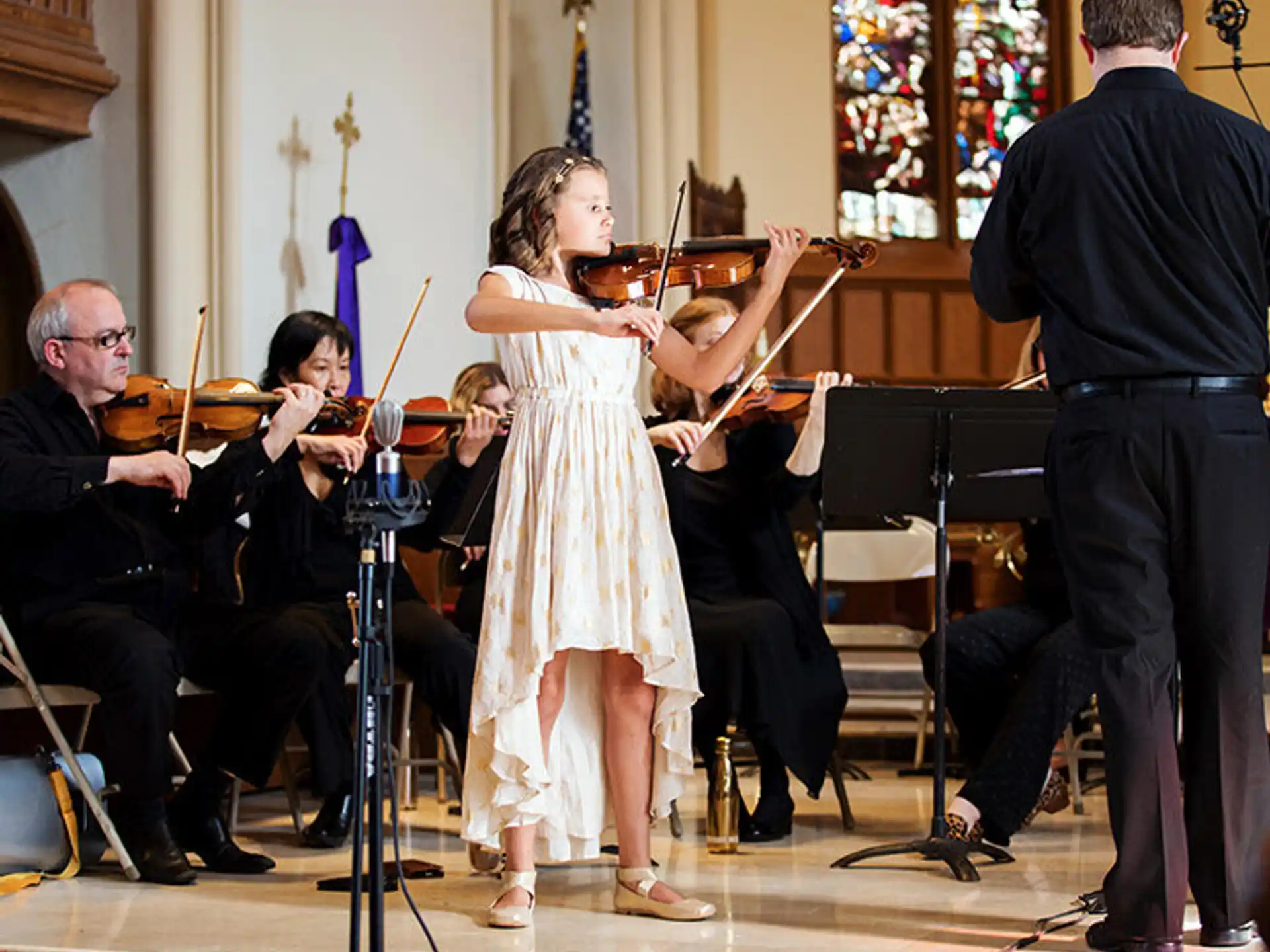 a girl in a white dress dancing with a man in a tuxedo and a woman in