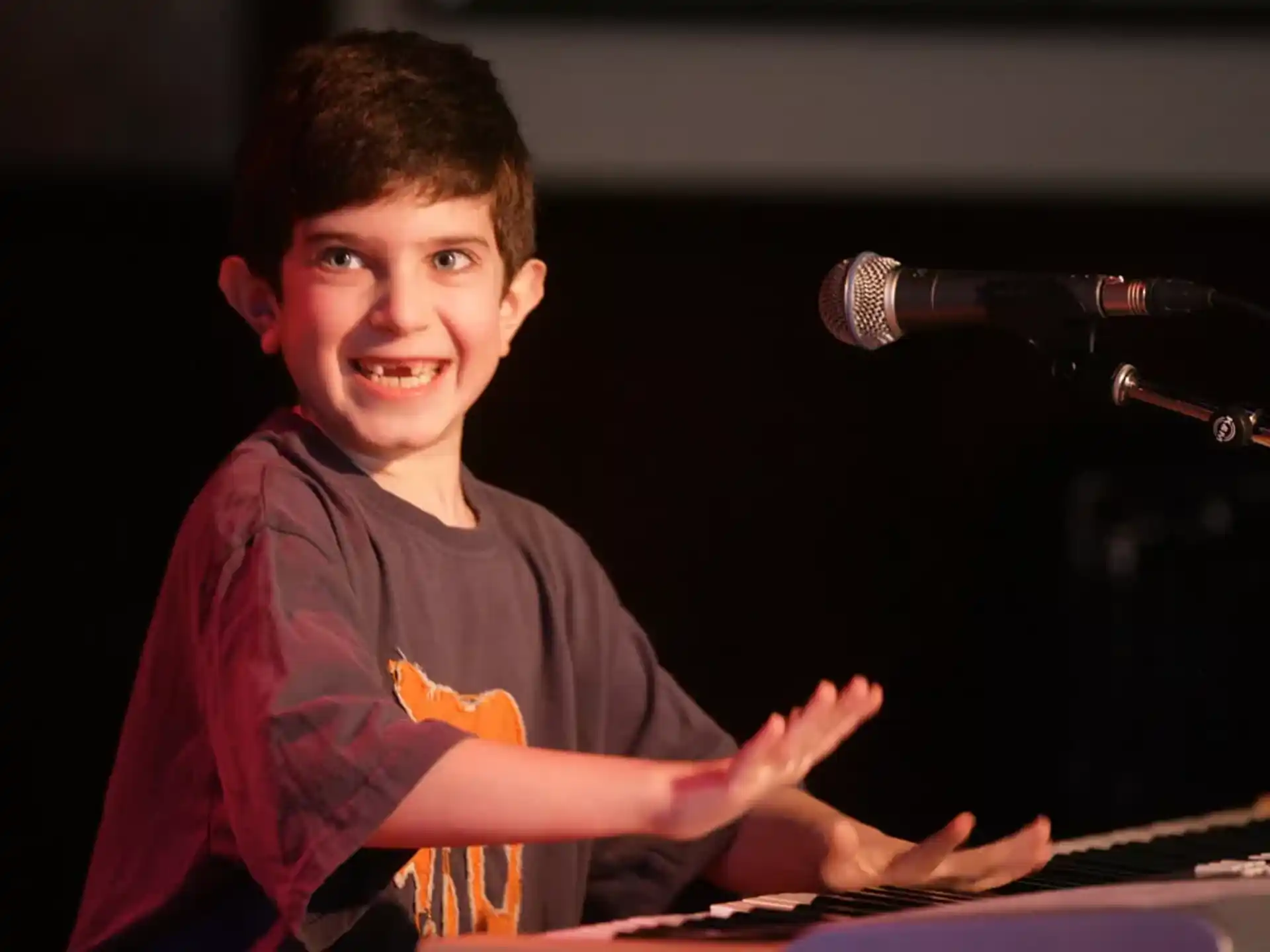 a boy smiling with a microphone