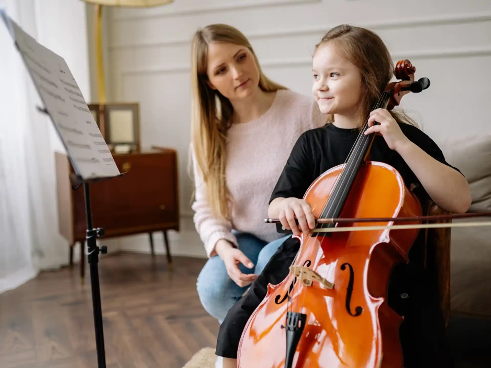 a woman playing a cello next to another woman