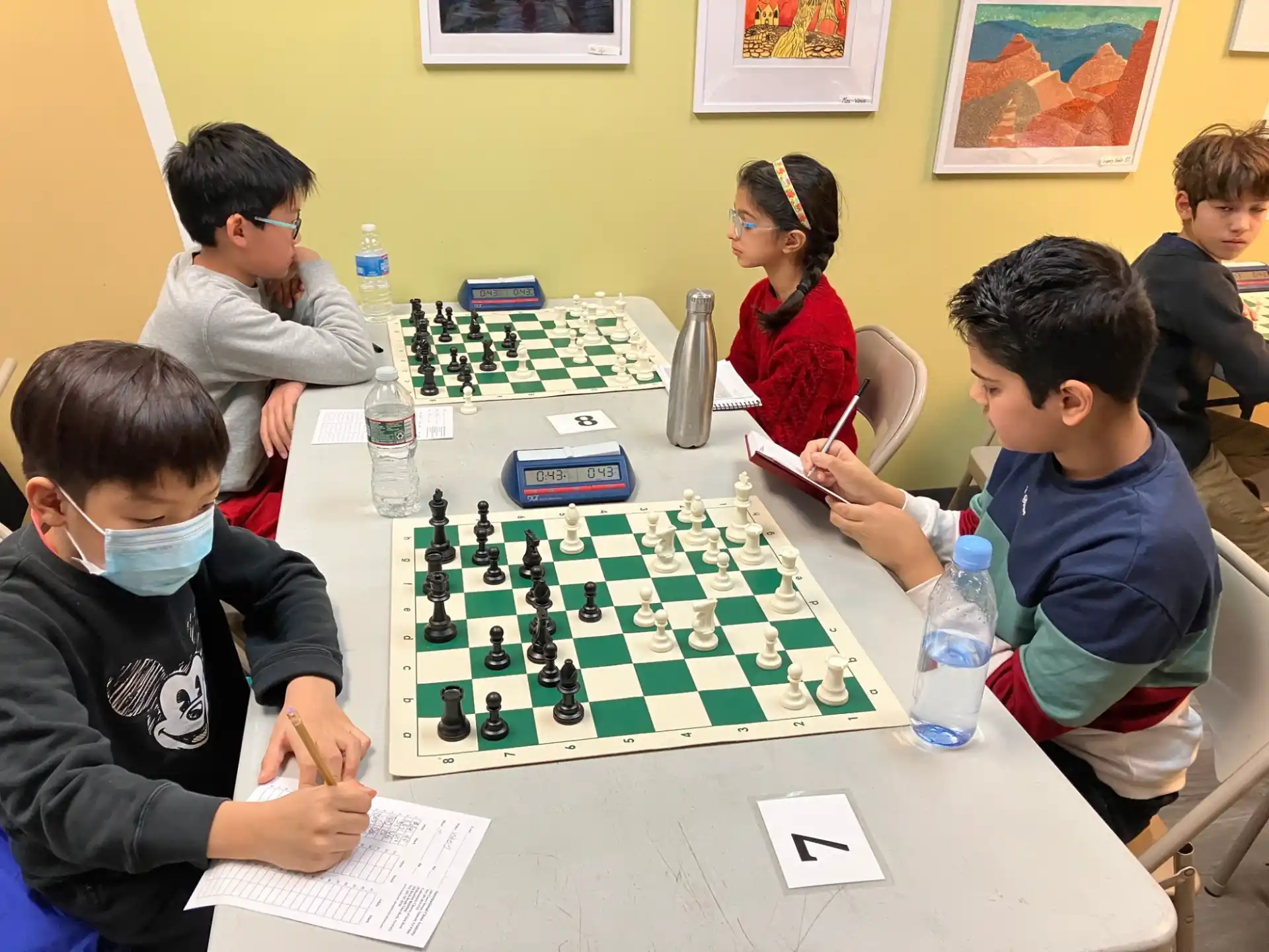 a group of people sitting around a table playing chess